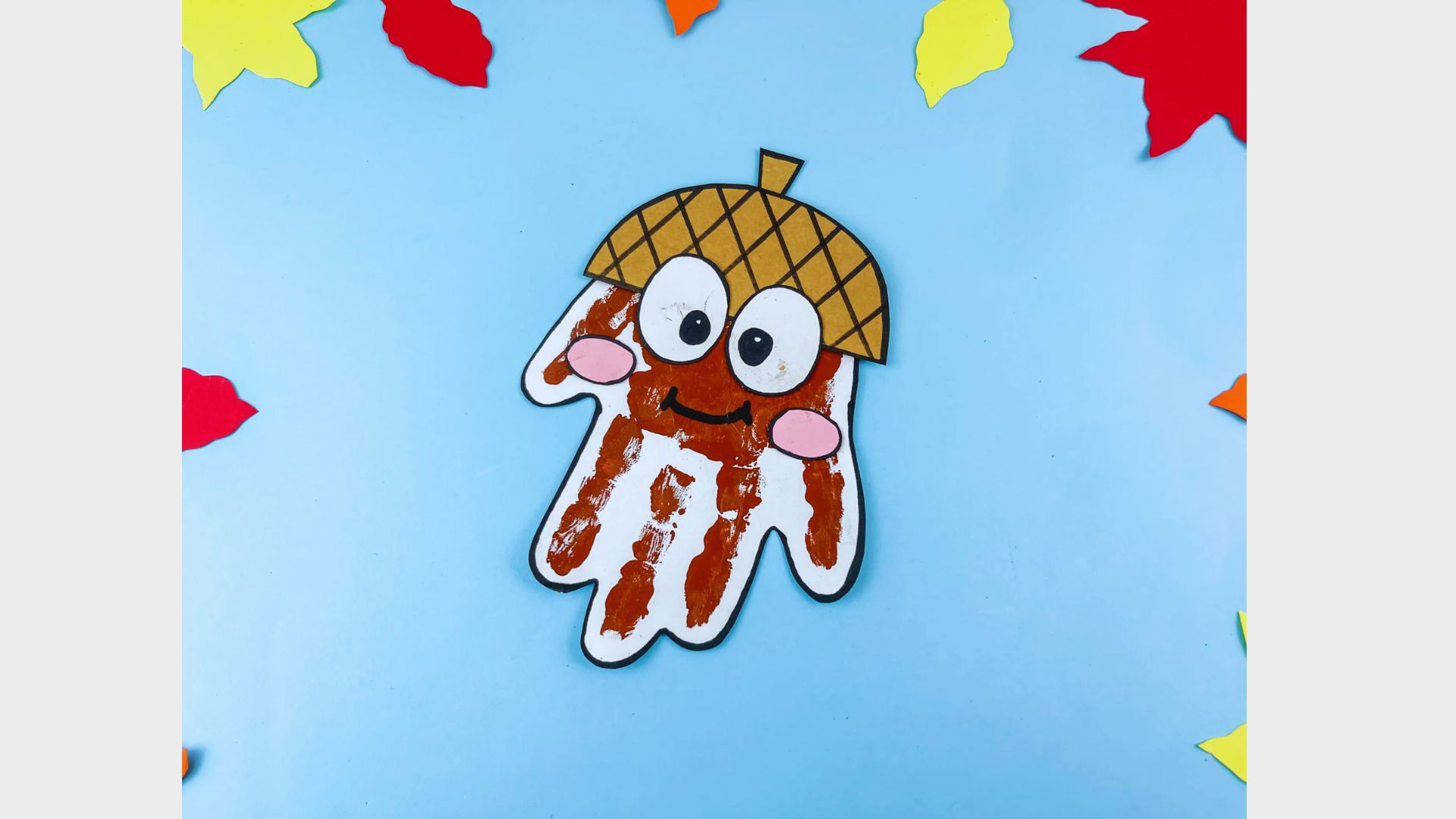 A child's handprint transformed into an acorn craft, featuring vibrant colors and playful design elements.