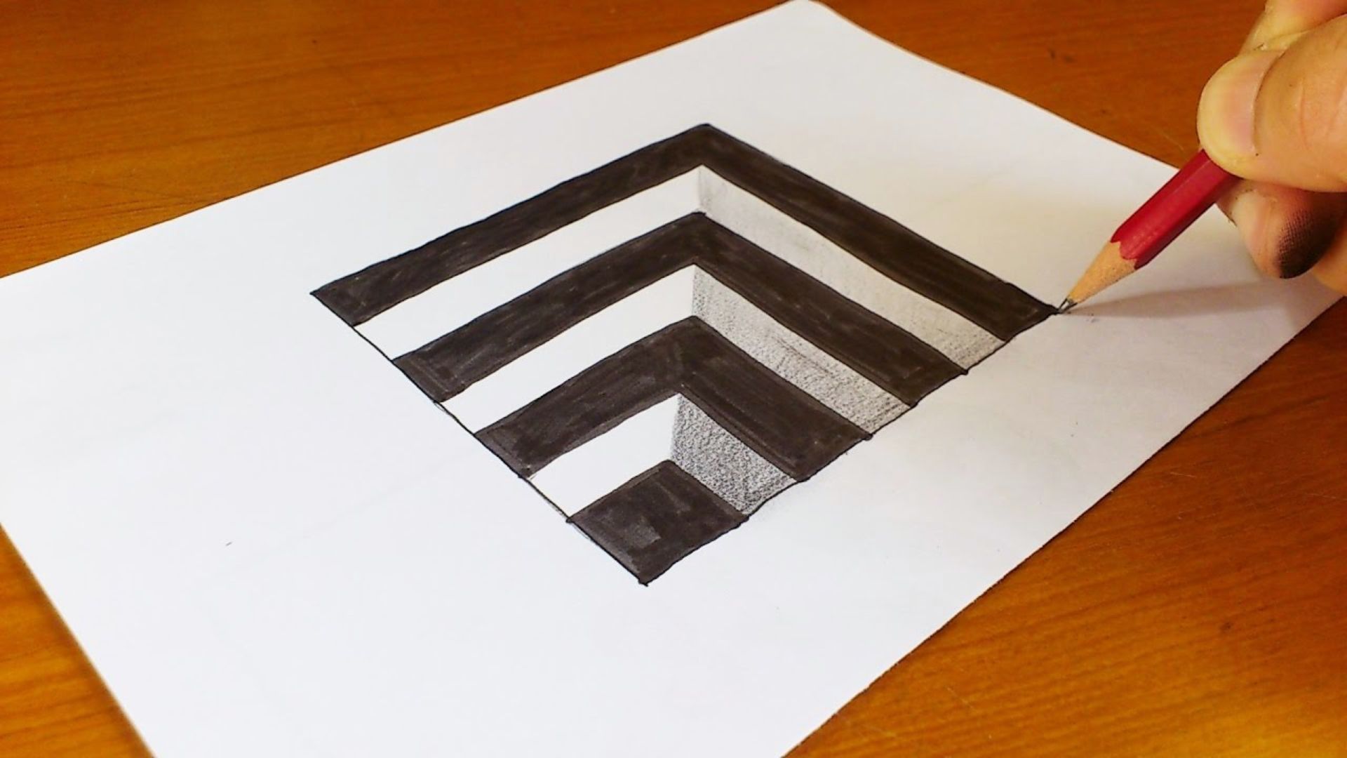 A person sketching a black and white chevron pattern on a sheet of paper