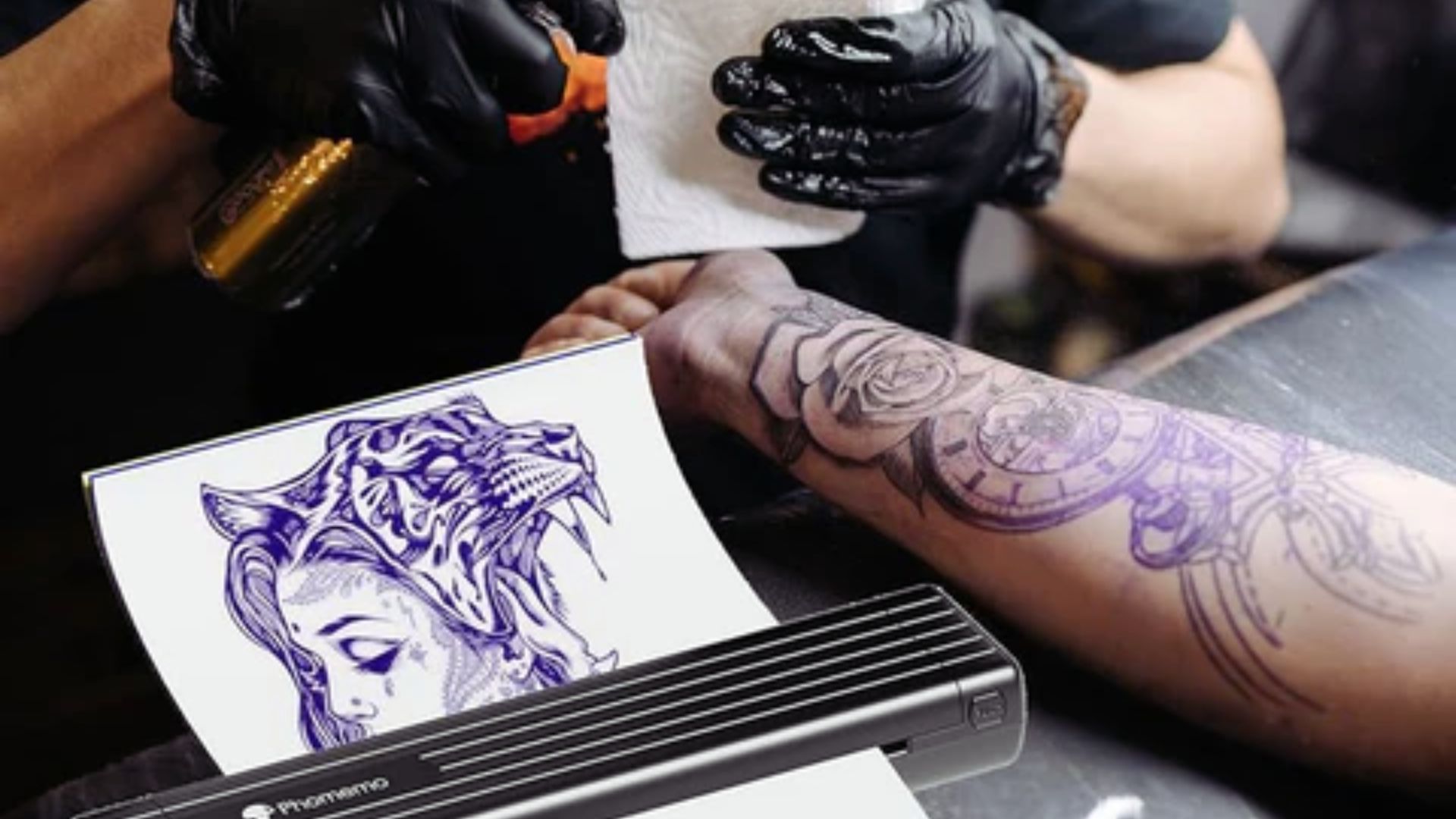 A man receives a tattoo as a machine applies ink to his skin in a tattoo studio setting.