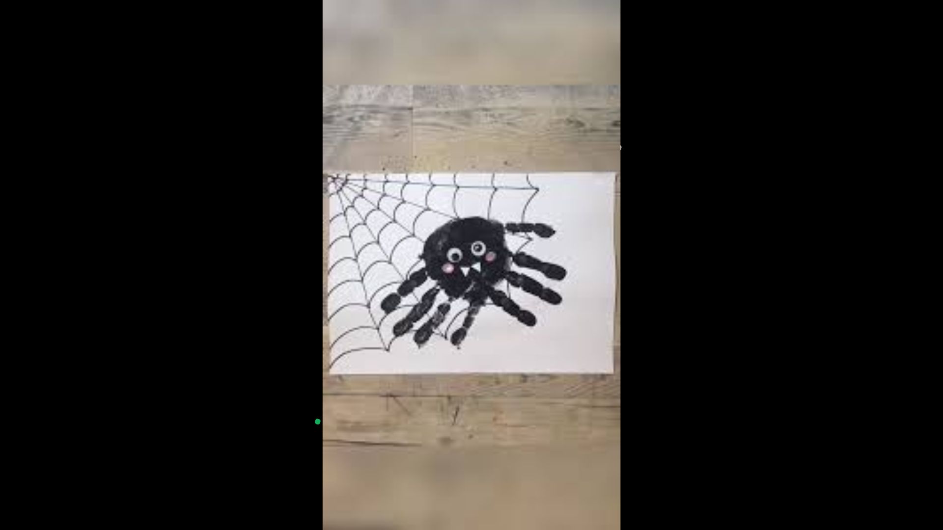 A close-up of a spider web featuring a black spider resting in the center, glistening with morning dew.