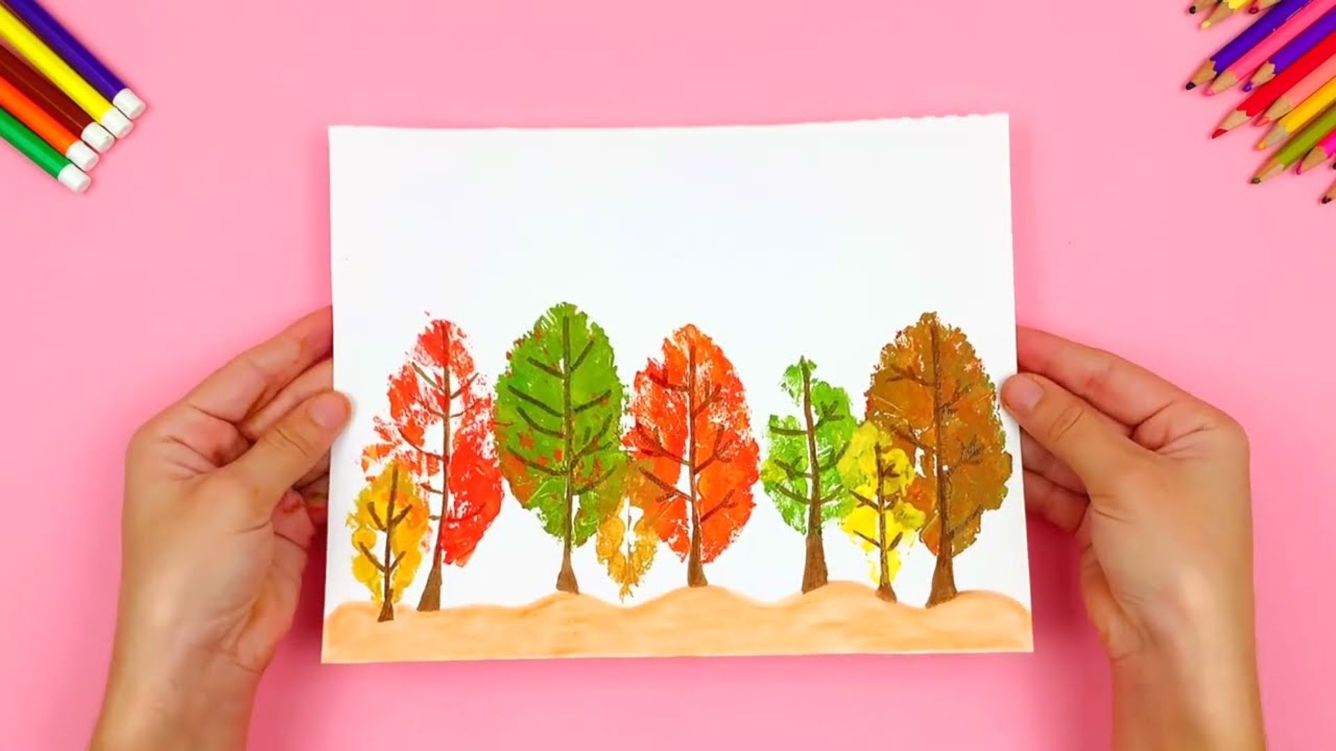 A person holds a drawing of trees on a piece of paper, showcasing their artistic interpretation of nature.