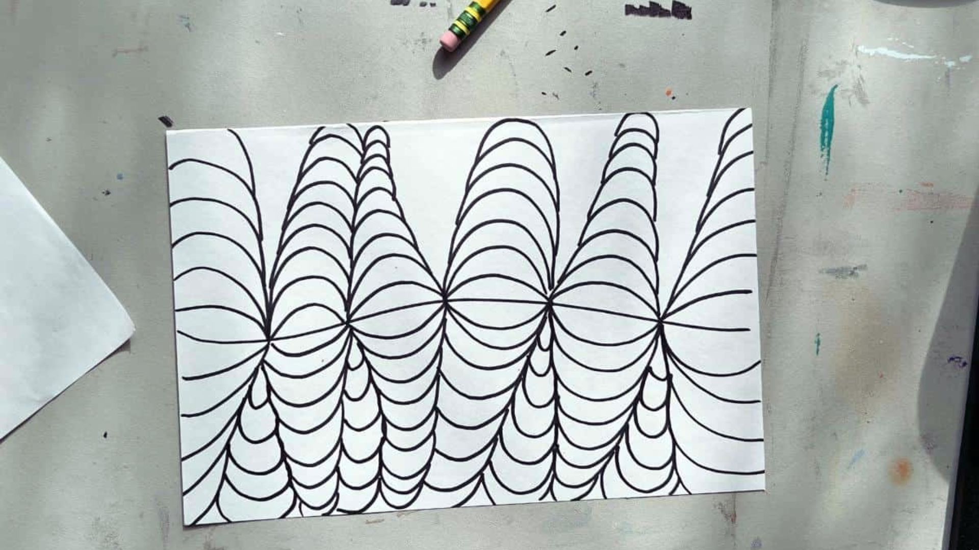 A piece of paper featuring a detailed drawing of a spider web, showcasing intricate lines and patterns.