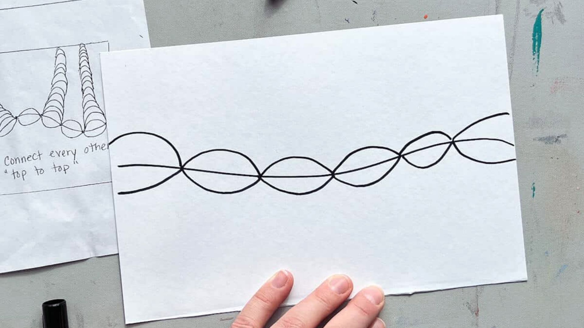 person holds a piece of paper featuring a hand-drawn spiral design, showcasing their artistic expression.