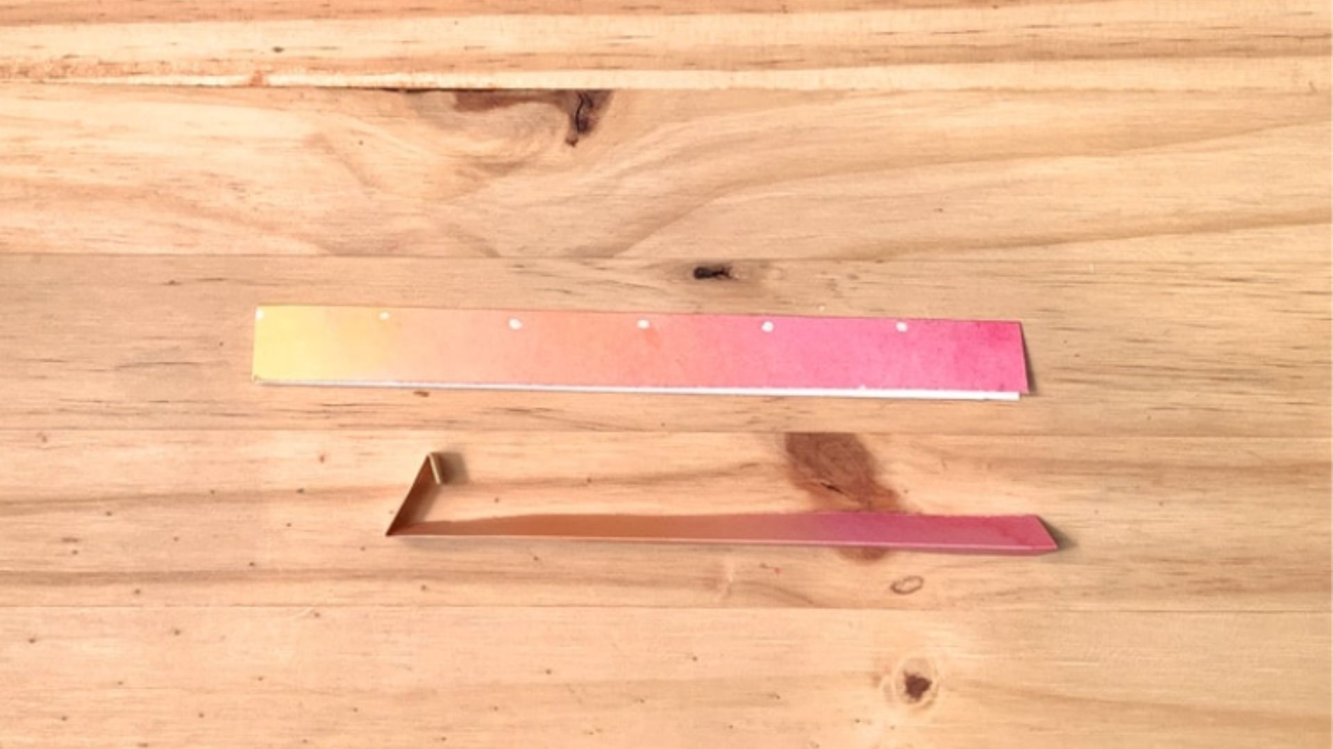 A pair of silver scissors resting on a wooden table, showcasing their sharp blades and ergonomic handles.