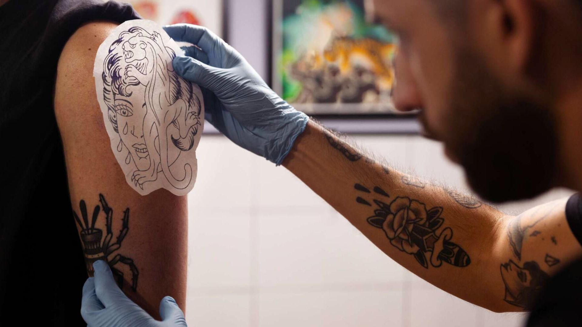 A man receiving a tattoo on his arm, focused on the artist's work and the design being inked.