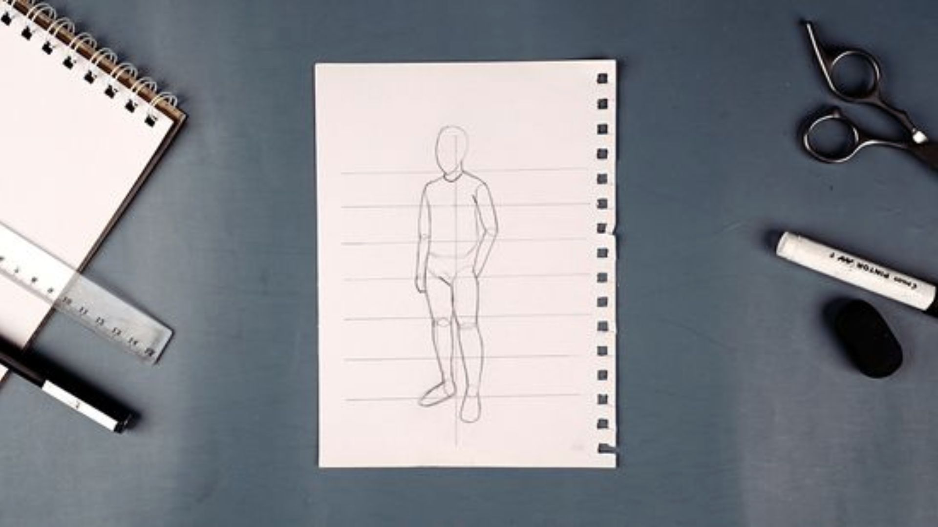 A drawing of a man on paper, accompanied by a ruler and scissors, illustrating a creative or crafting process.