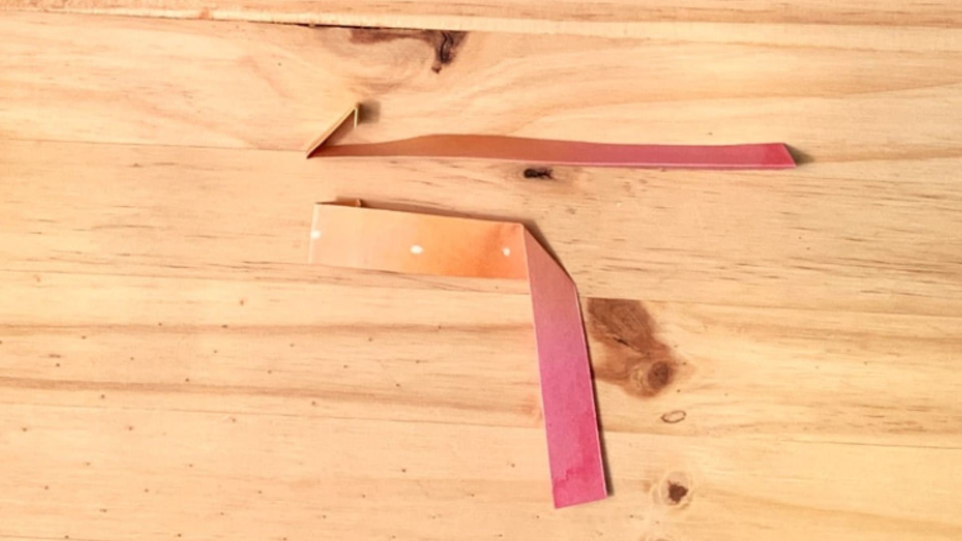 A piece of paper adorned with a pink and orange ribbon, elegantly tied at the top.
