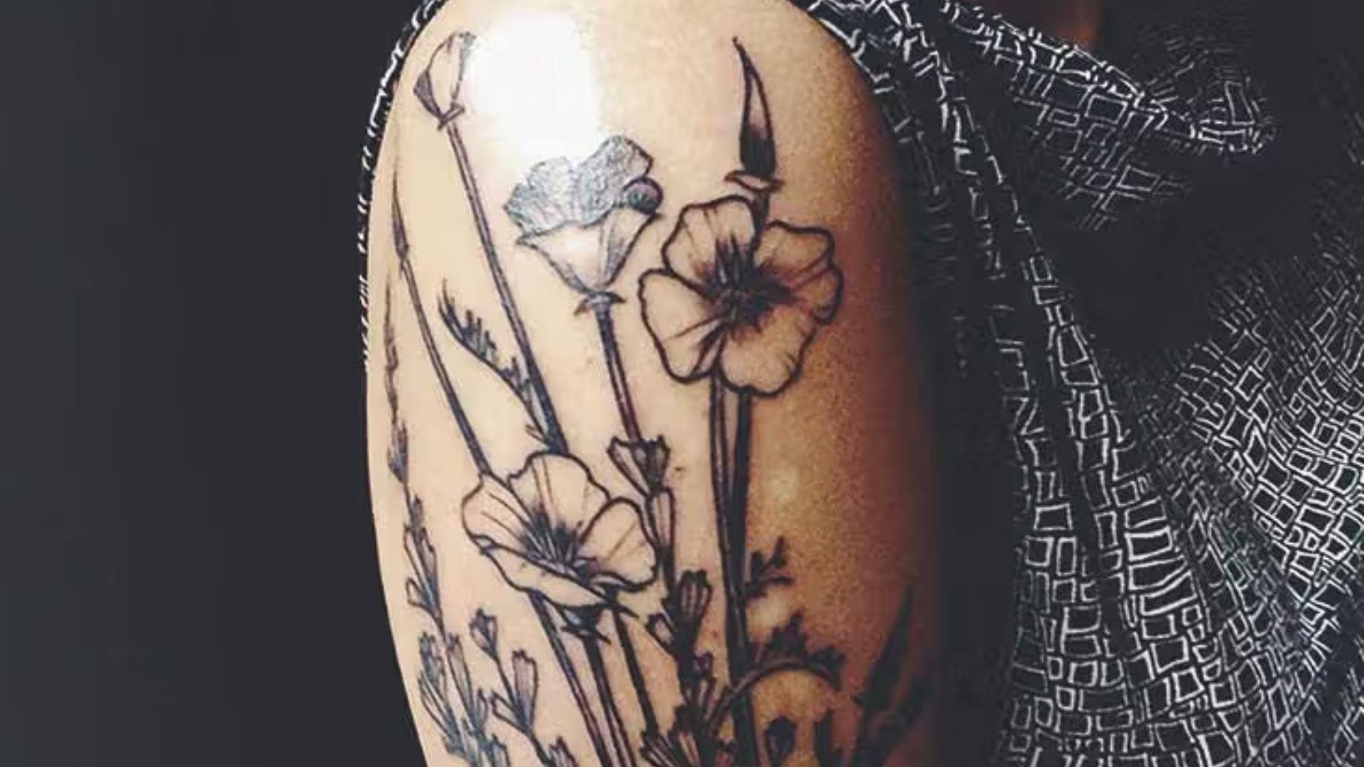 A woman's arm adorned with a colorful flower tattoo, highlighting its artistic design.