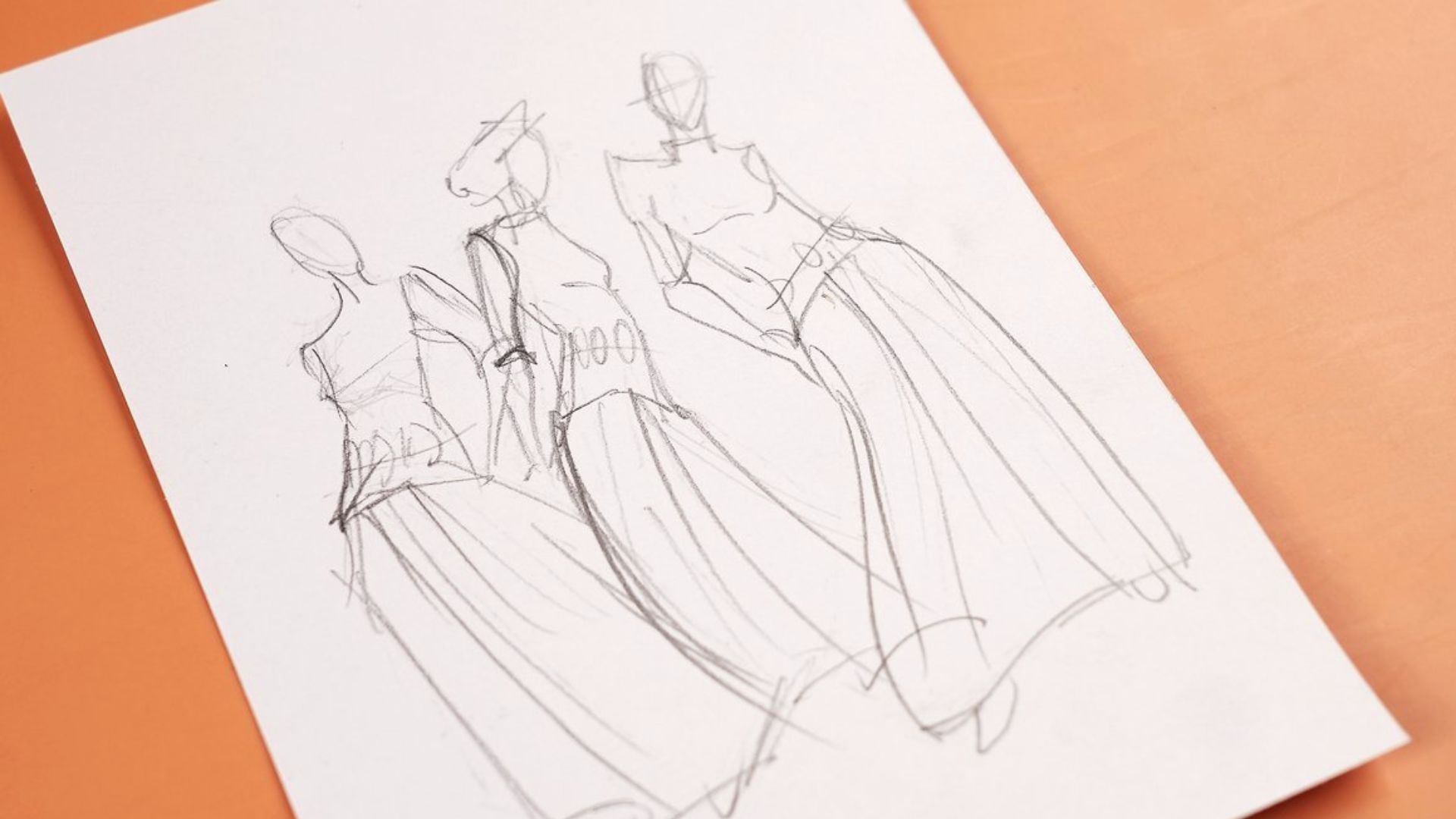 A sketch depicting three women in elegant dresses on a sheet of paper, showcasing their unique styles and poses.