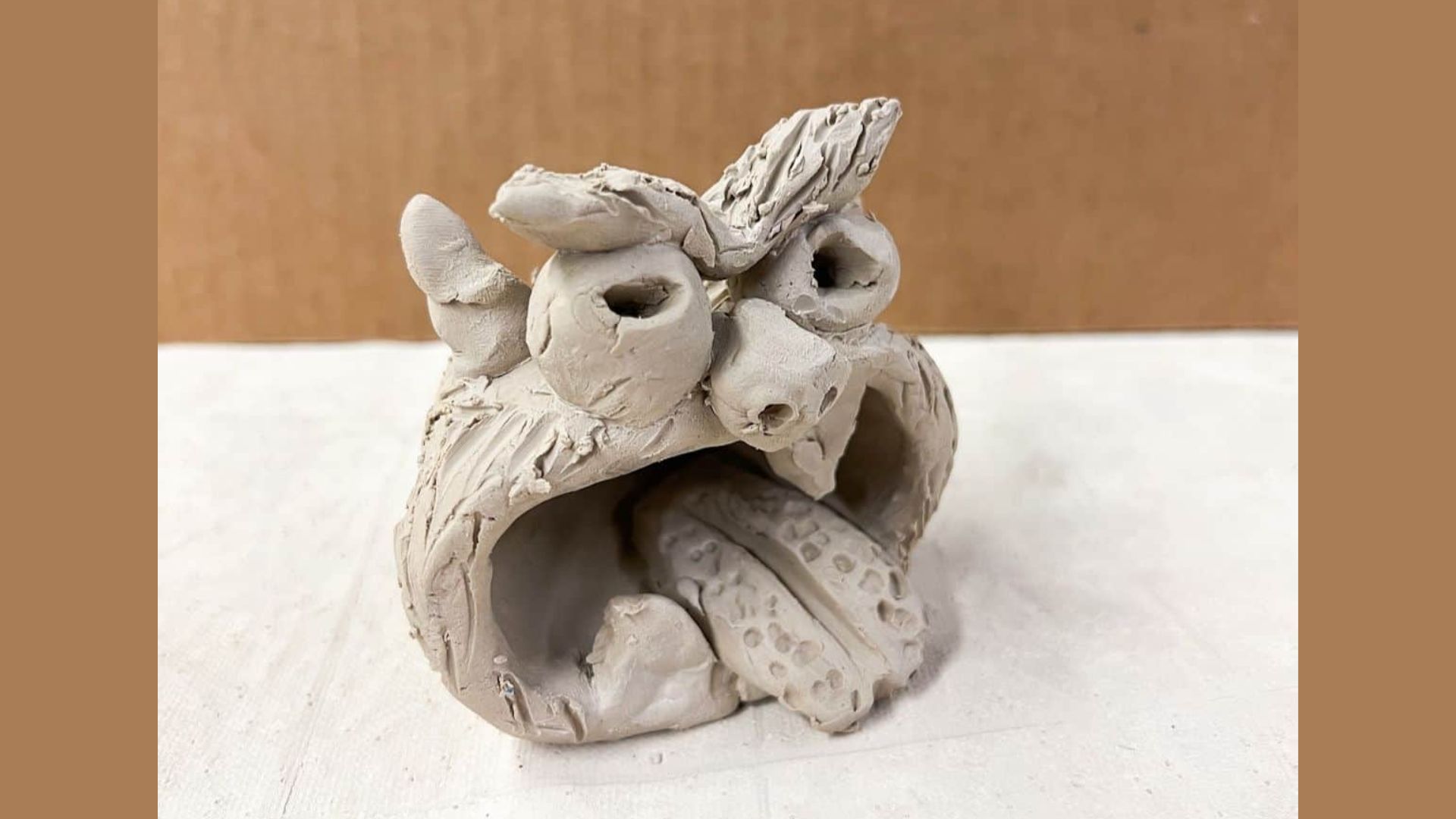 Clay sculpture of an owl, showcasing intricate details and a naturalistic design.