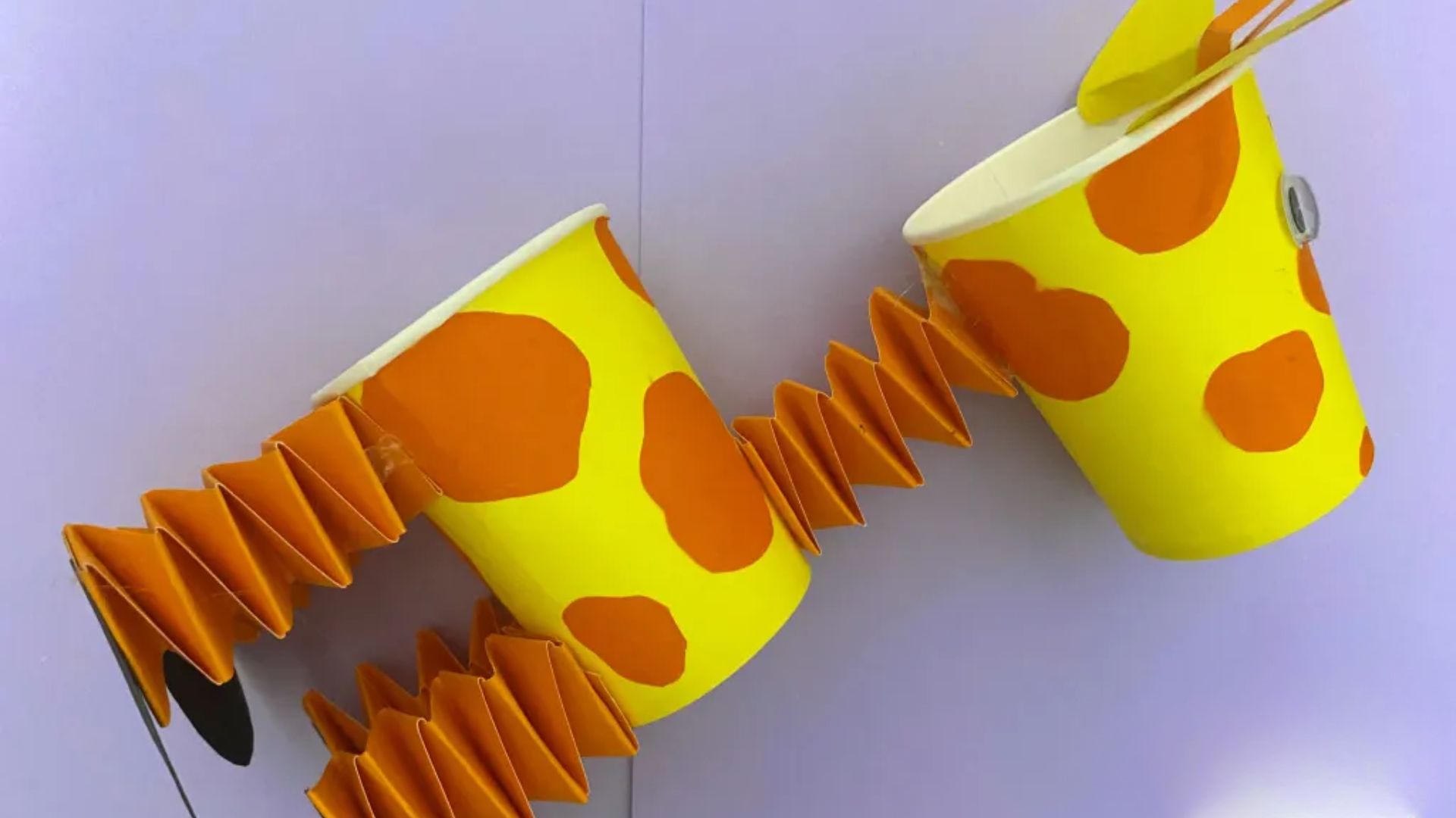 A playful giraffe cup with a straw, used in a creative project that encourages tactile exploration and spatial awareness.