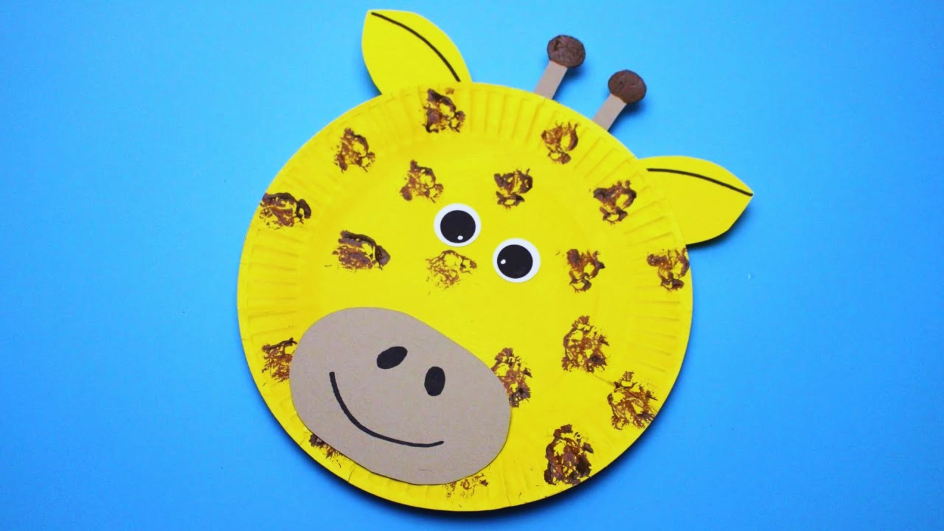 Colorful paper plate giraffe craft for kids, featuring yellow and brown spots, with googly eyes and a cheerful expression.