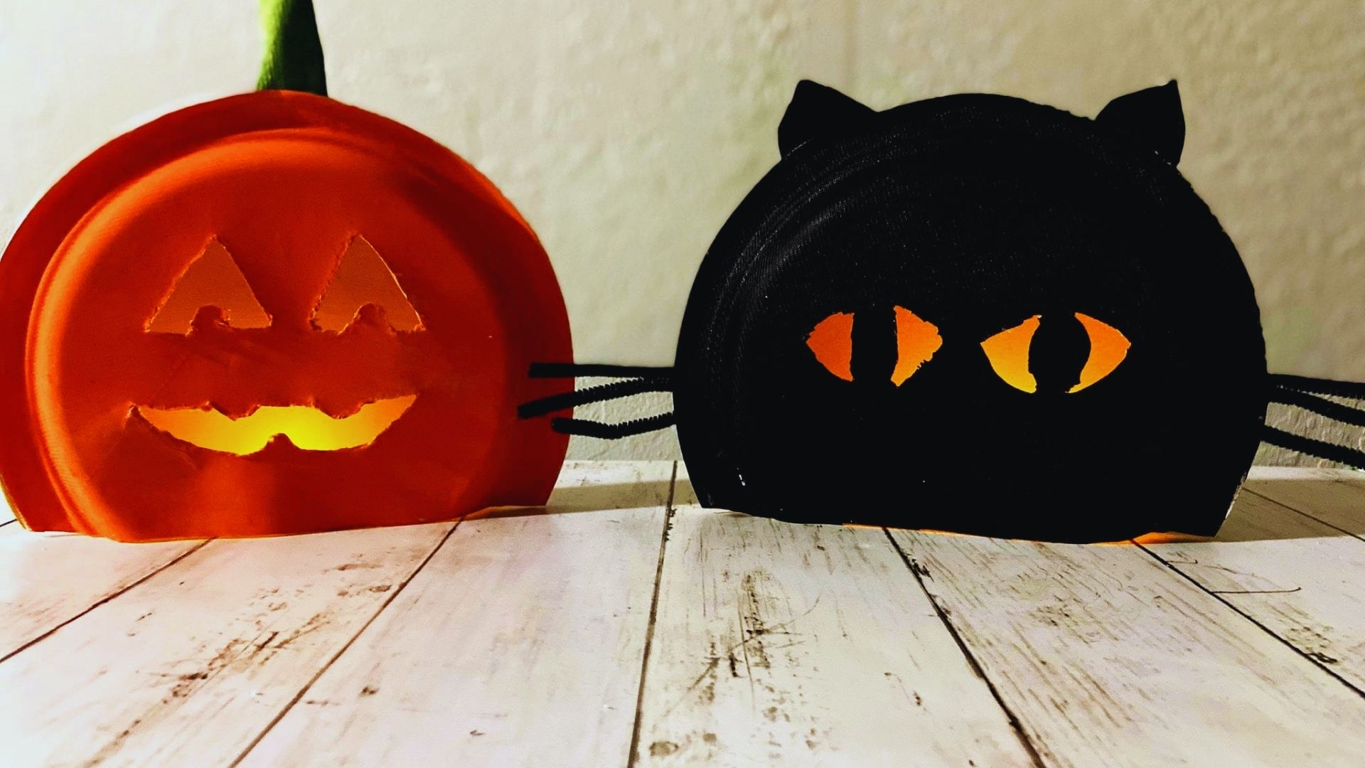 Two paper plates with Halloween pumpkins and cat faces