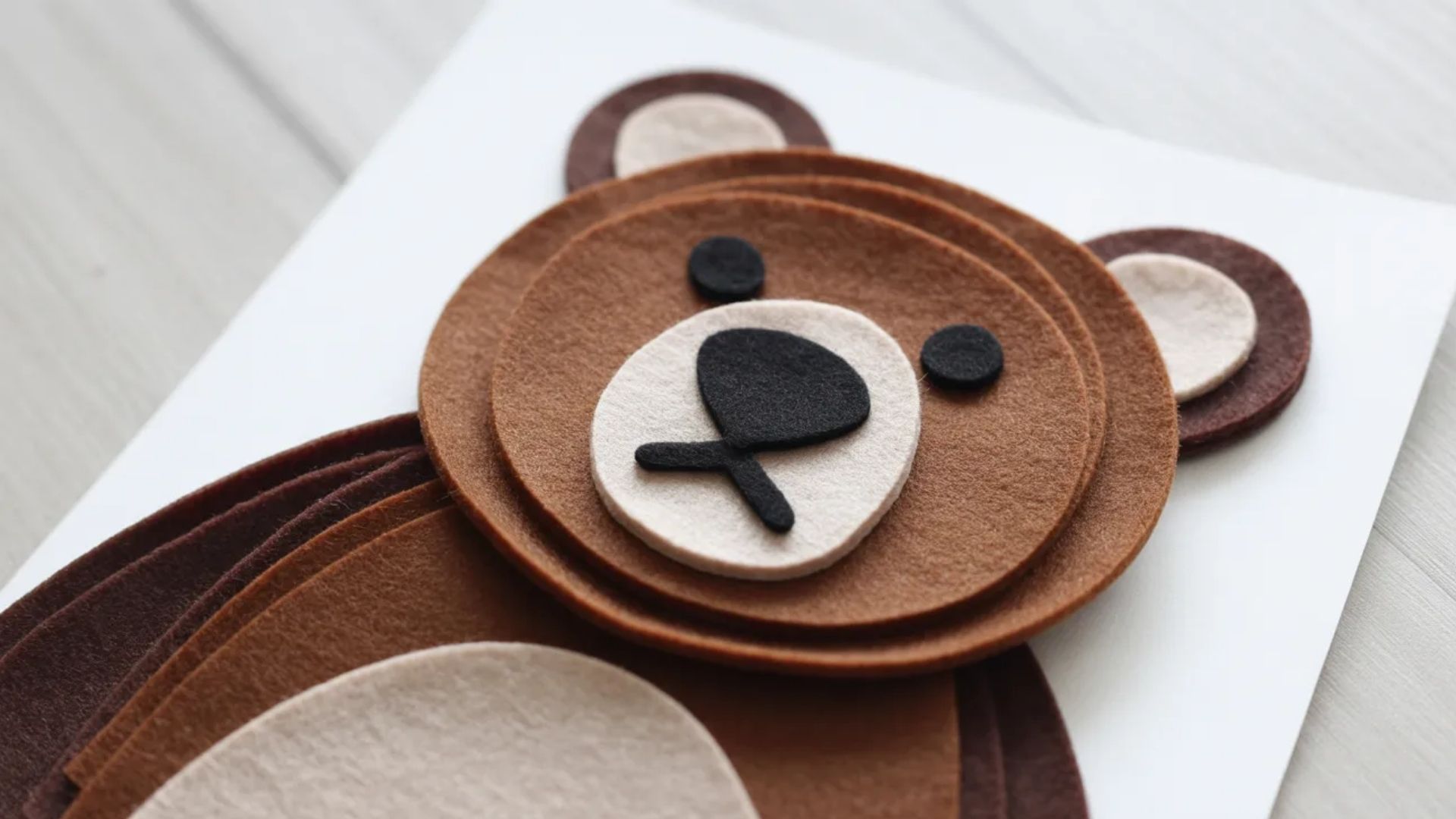 A brown bear card featuring felt eyes, showcasing a cute and playful design for greeting or decoration purposes.