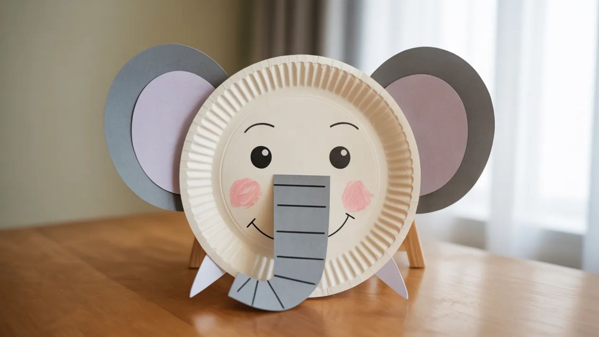 A colorful paper plate crafted into an elephant, featuring ears, trunk, and eyes, showcasing a fun art project for children.