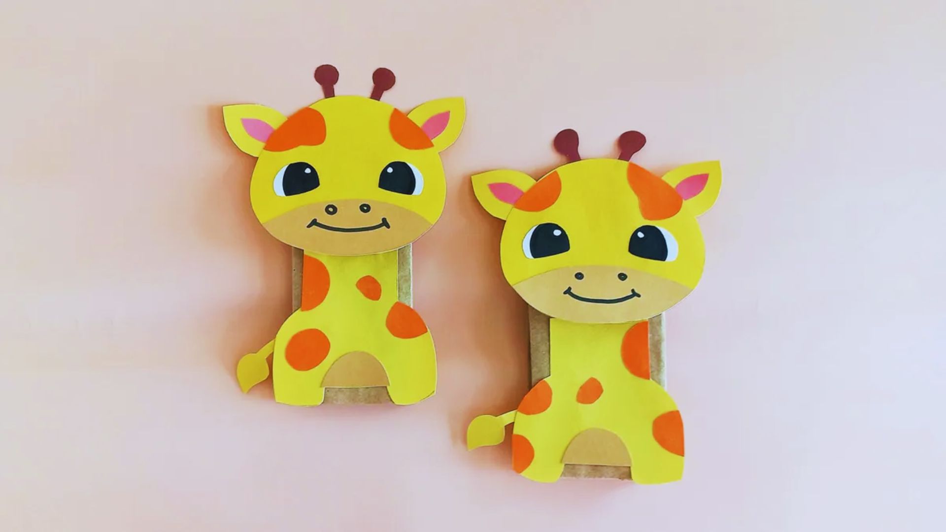 A pair of giraffe-shaped paper clips rests on a pink wall, showcasing a whimsical design for organizing papers