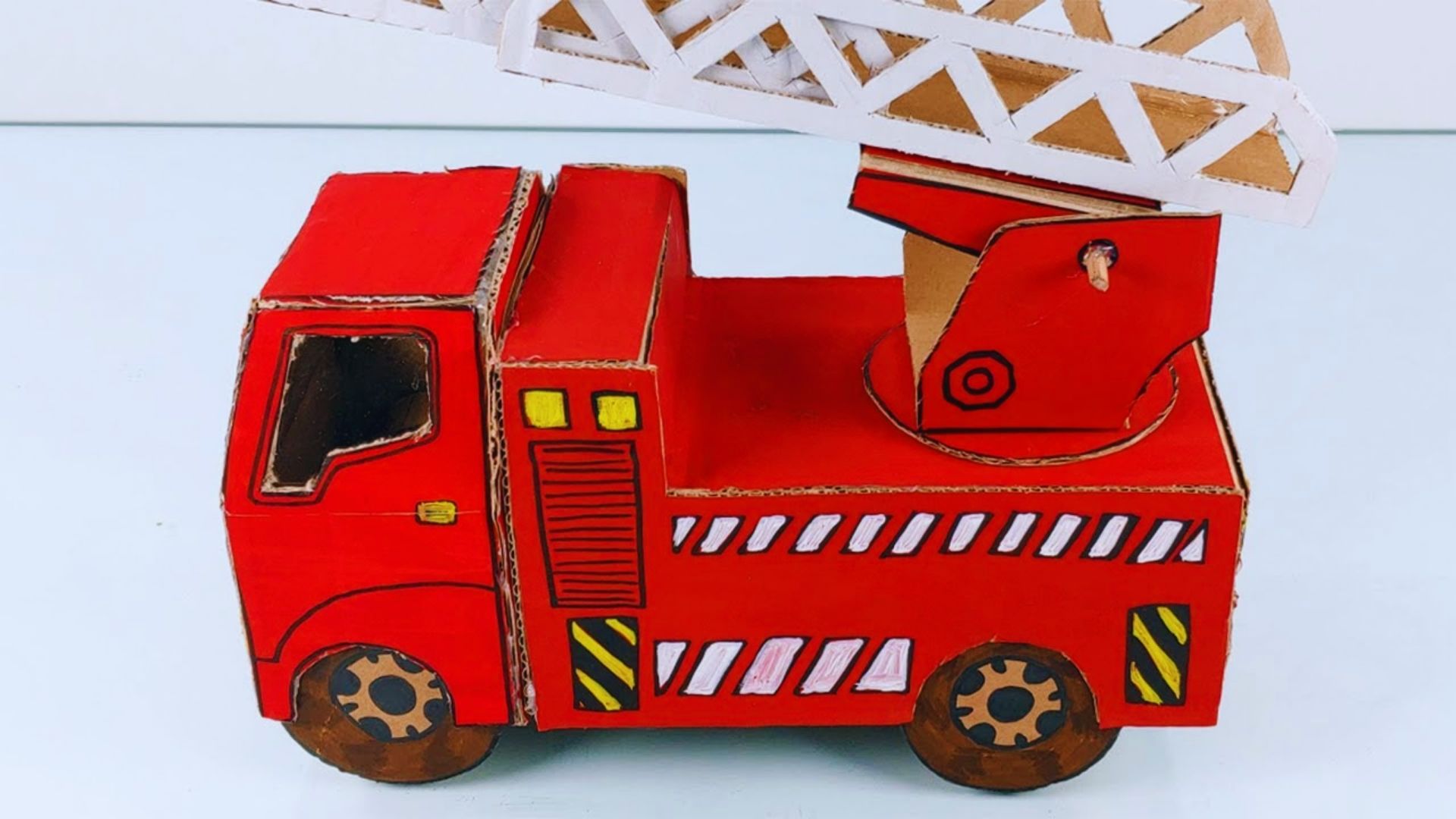 A colorful cardboard fire truck craft featuring a crane on top, showcasing creativity and imaginative play.