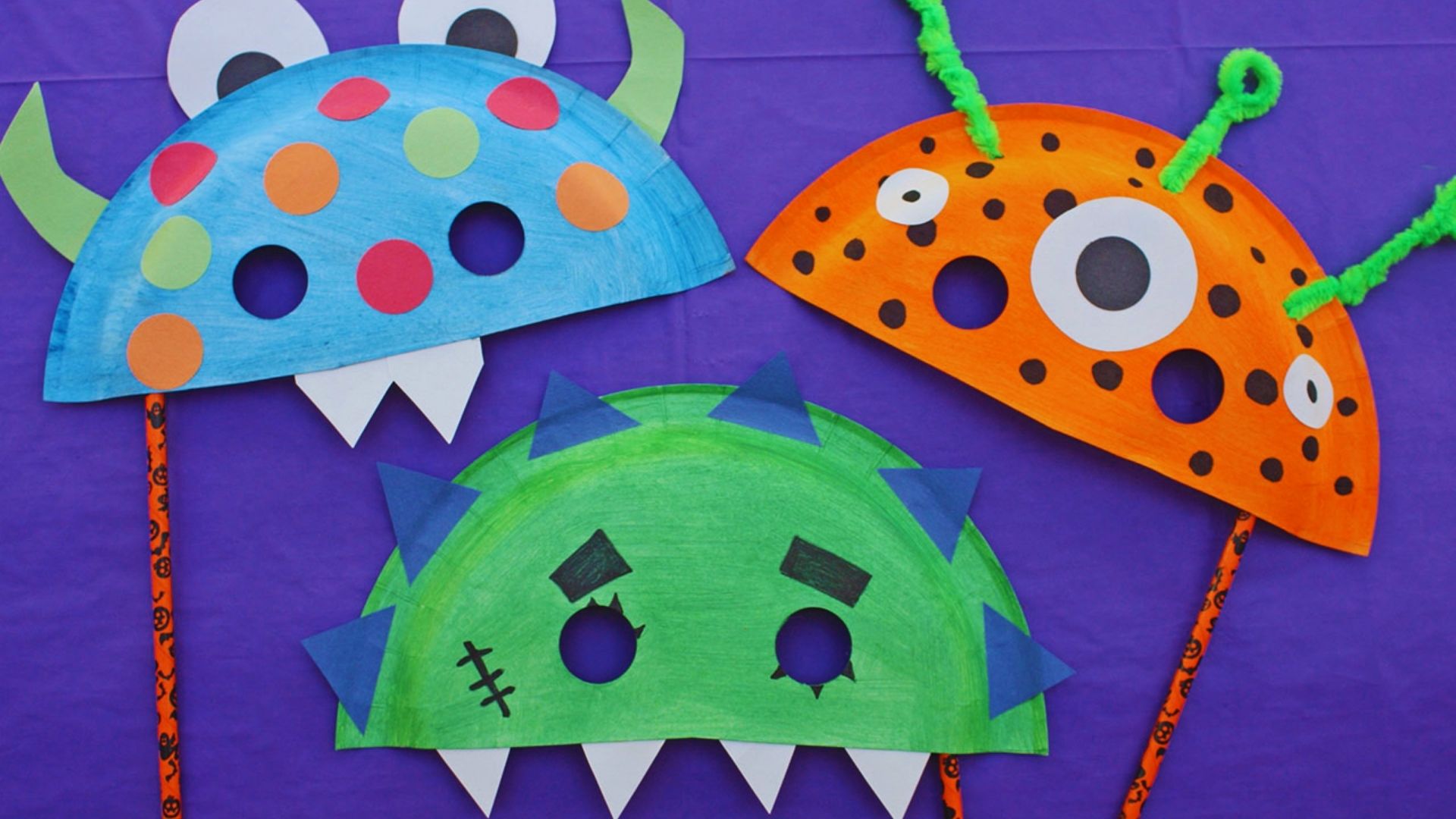 Three colorful paper plate monster masks featuring various eyes and mouths, arranged for display.