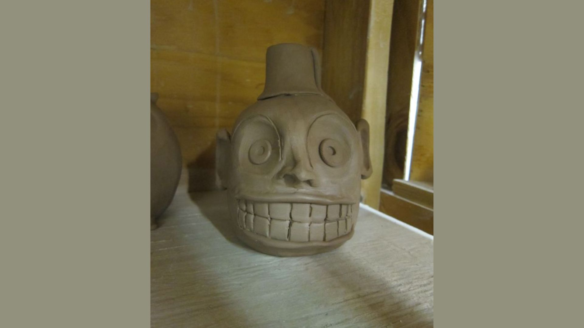 A ceramic vase featuring a stylized face design, showcasing artistic craftsmanship and unique character.