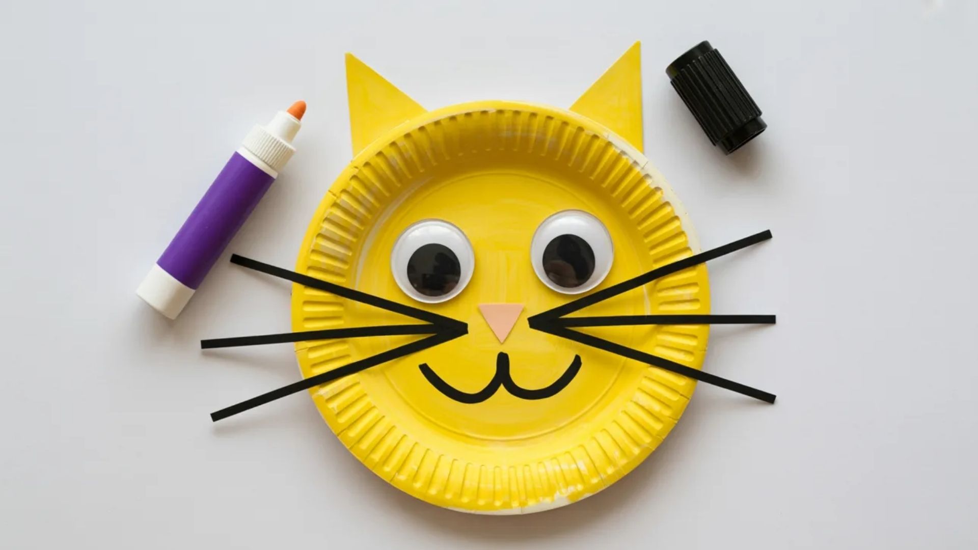 A colorful paper plate cat craft decorated with glue and markers, showcasing playful features and vibrant colors.