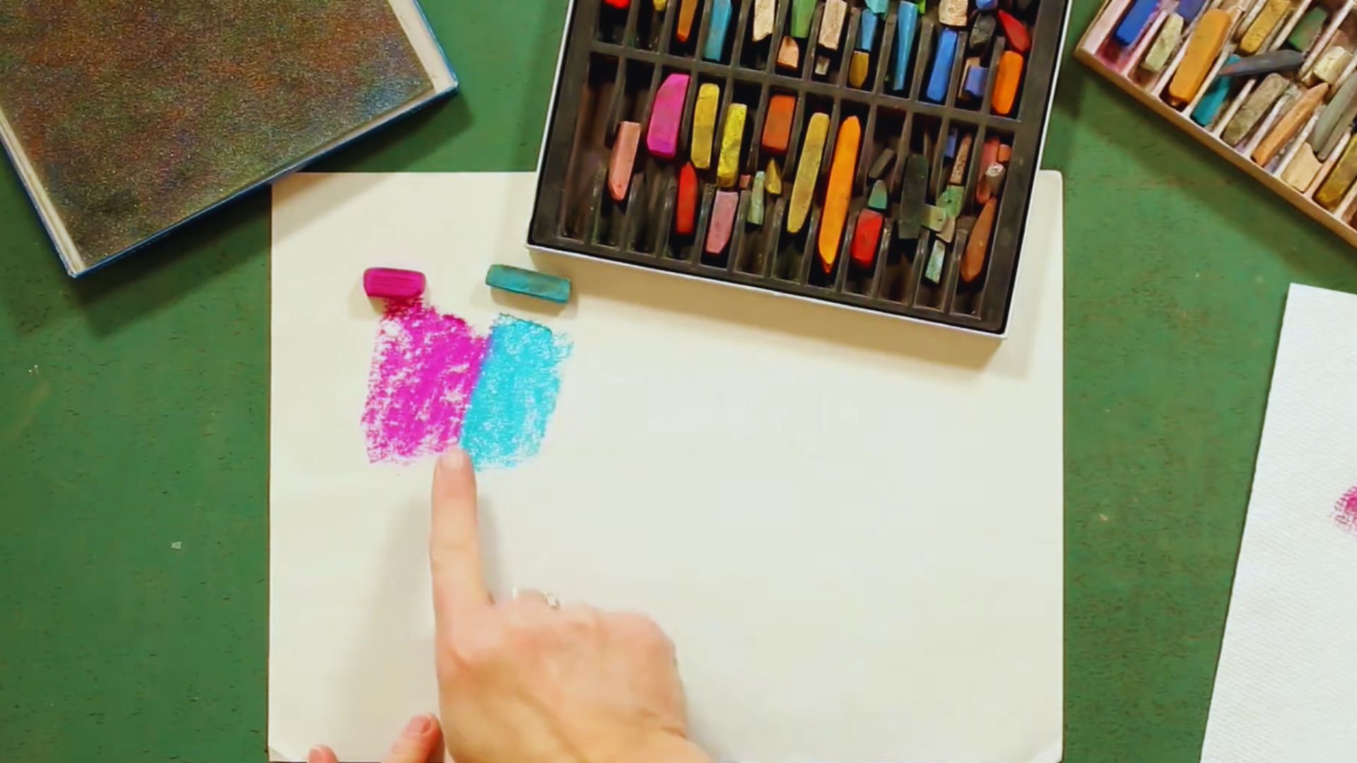 A person holds a paintbrush, creating artwork on a sheet of paper.