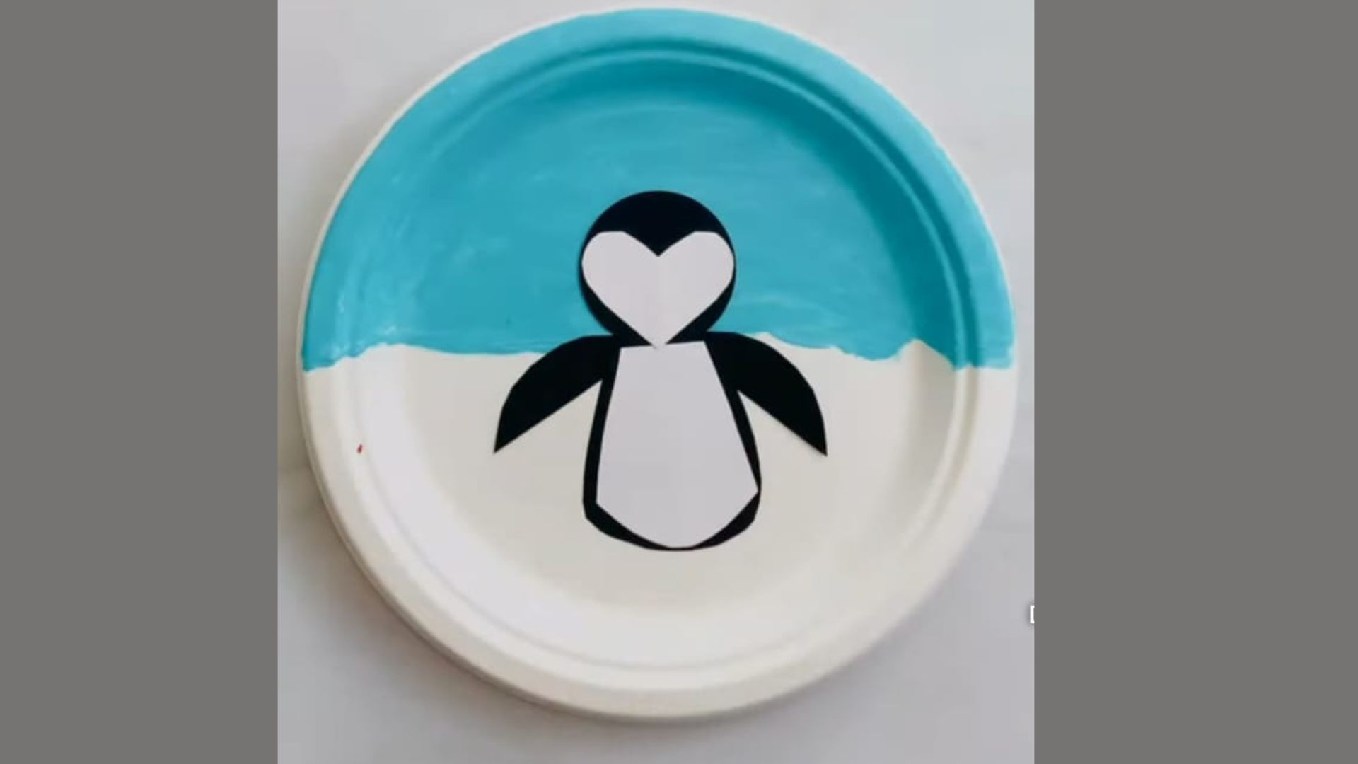 A painted penguin on a plate, set against a vibrant blue background.