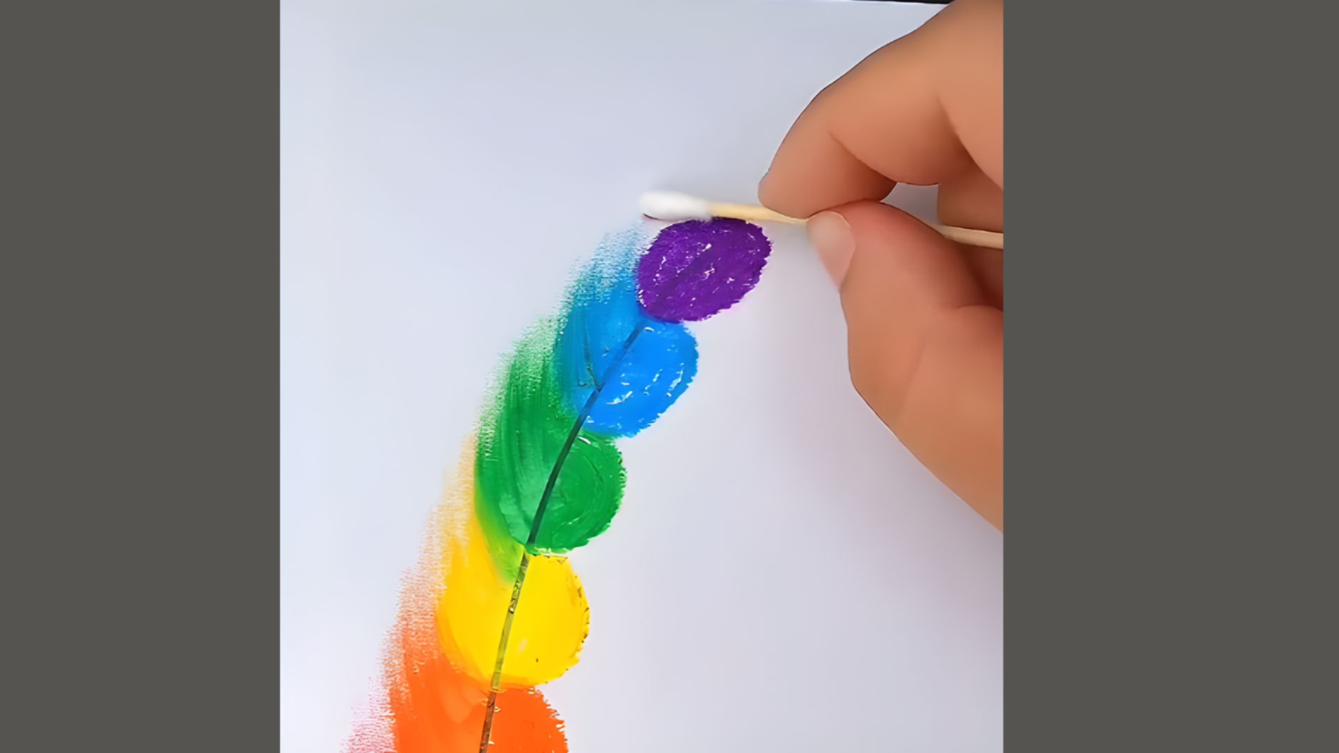 A person paints a vibrant rainbow on a canvas using a brush, showcasing bright colors and artistic expression.