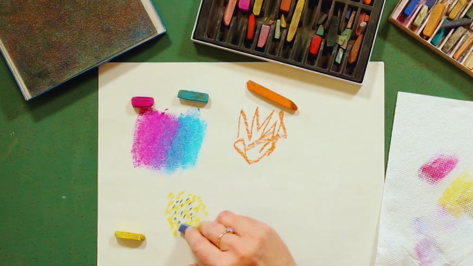 An individual is creating artwork on paper with an assortment of colored pencils.