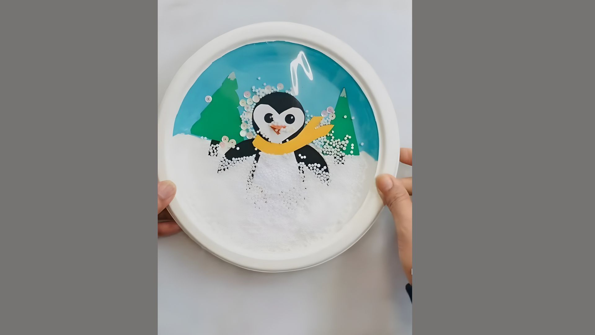 A person holds a small plate featuring a cute penguin design, showcasing a whimsical and playful aesthetic.