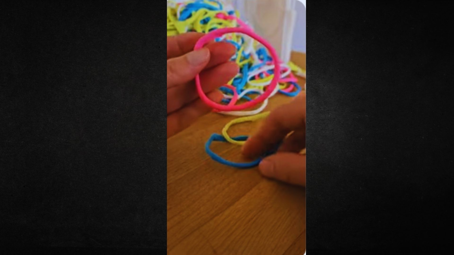 A hand grips a colorful rubber band, displaying its vivid hues and flexible texture.