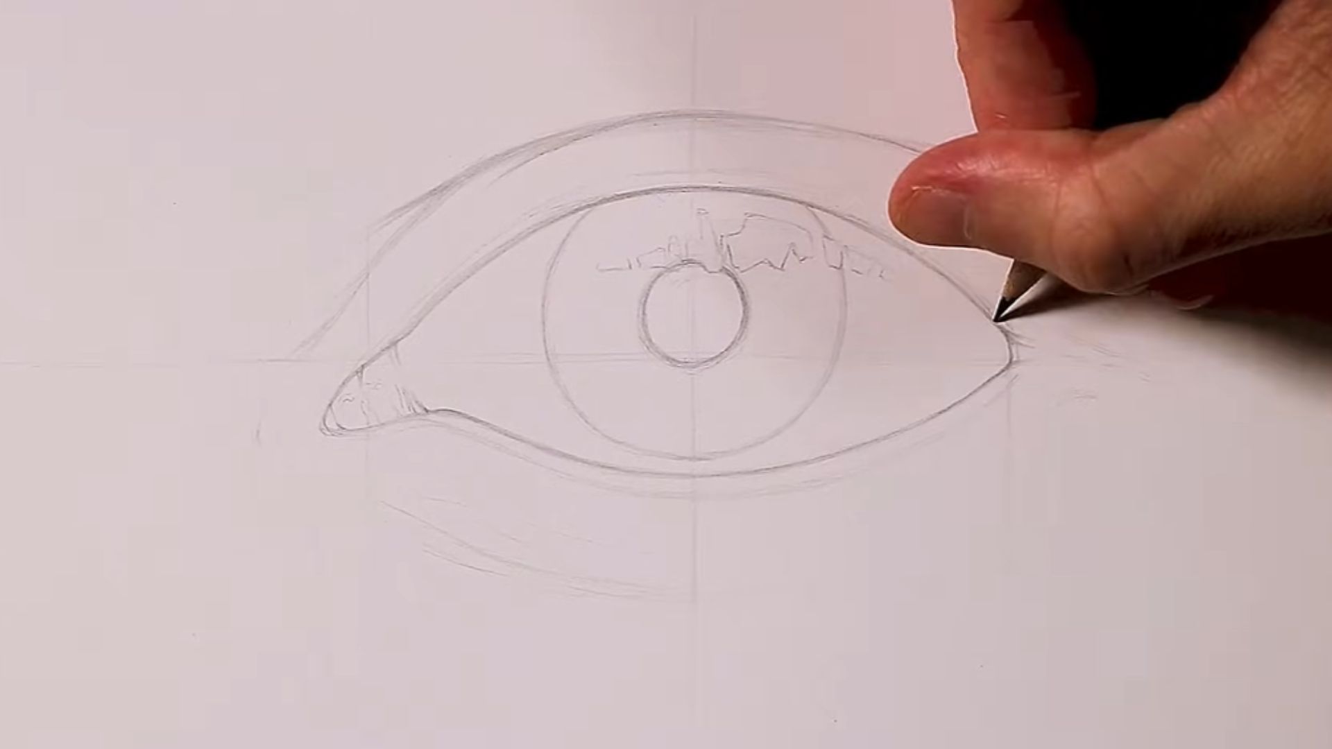 A person sketching an eye with a pencil on a blank sheet of paper, focusing intently on the details.