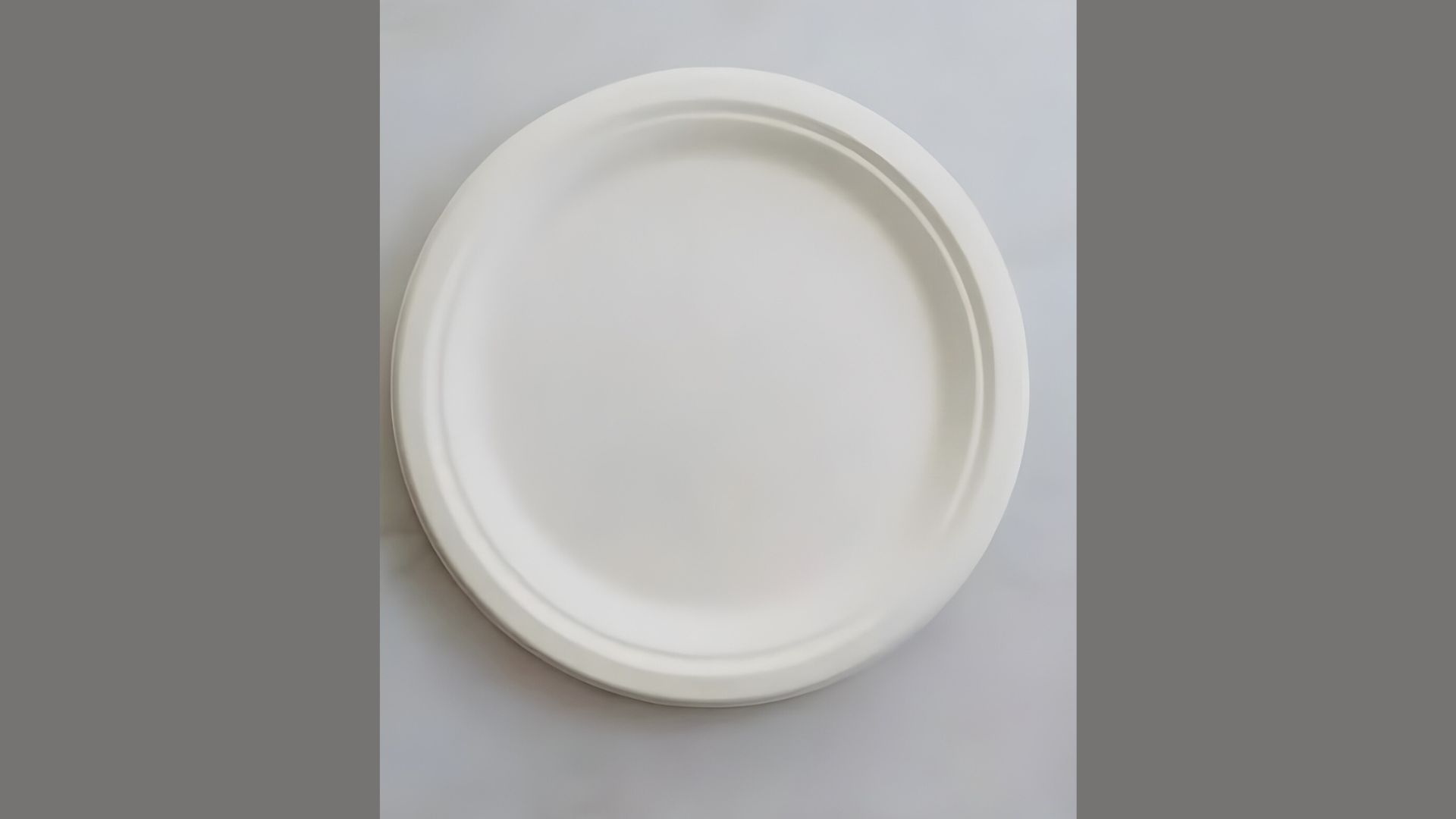 A circular white plate resting on a white surface, creating a seamless and minimalist appearance.