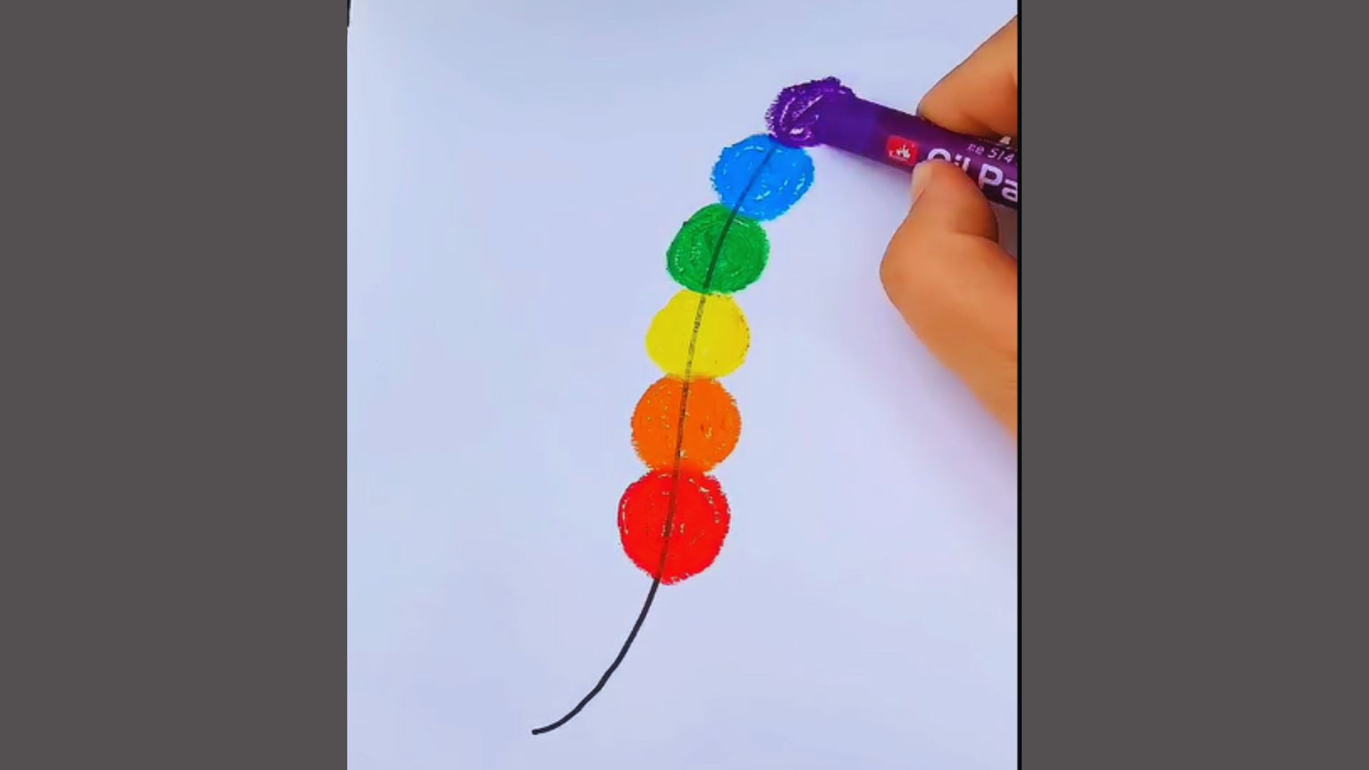 A person skillfully draws a vibrant rainbow-colored string on a surface, showcasing a blend of bright colors.