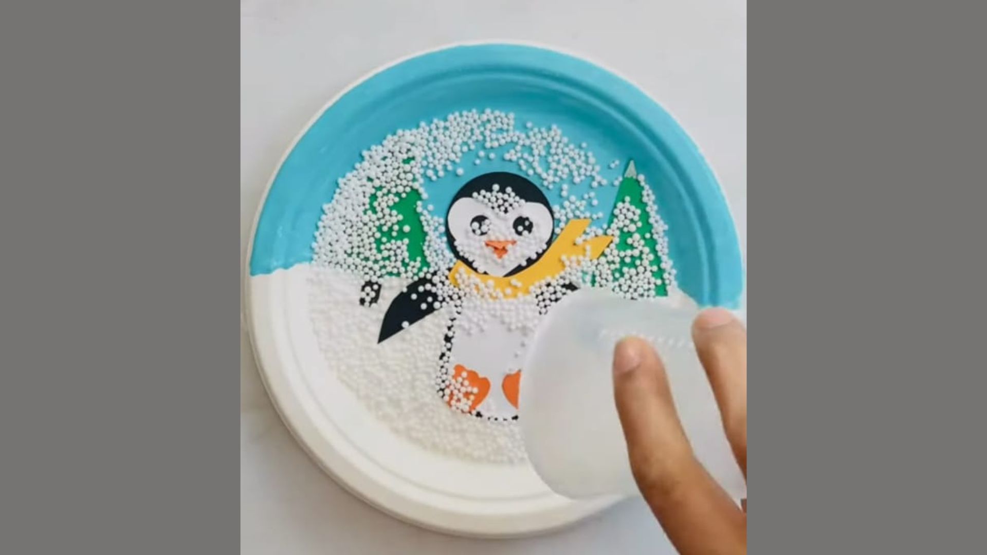 . A person holds a plate featuring a small, decorative penguin on it, showcasing a whimsical presentation.