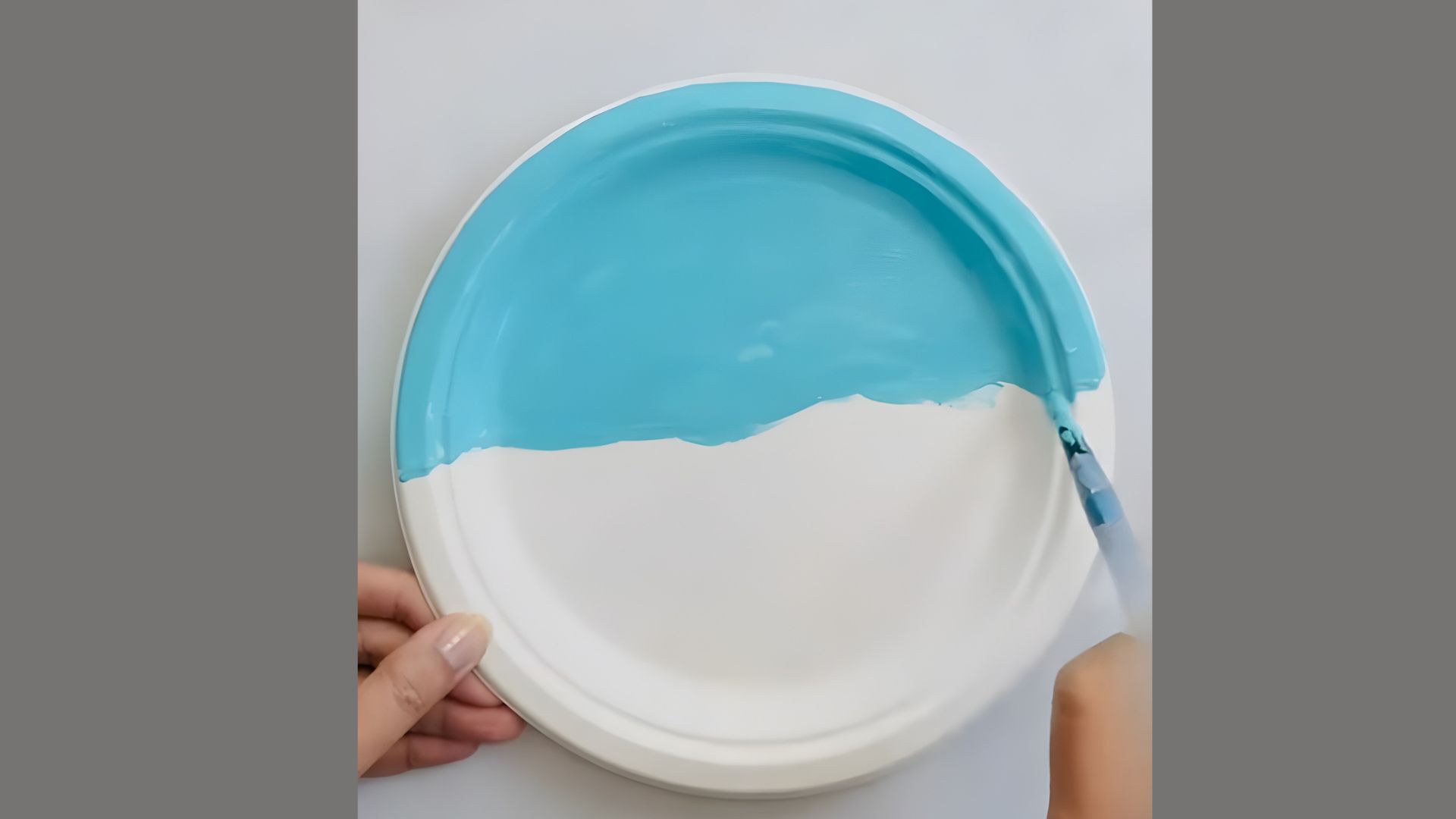 A person paints a plate with blue and white paint, focusing on intricate designs and patterns.