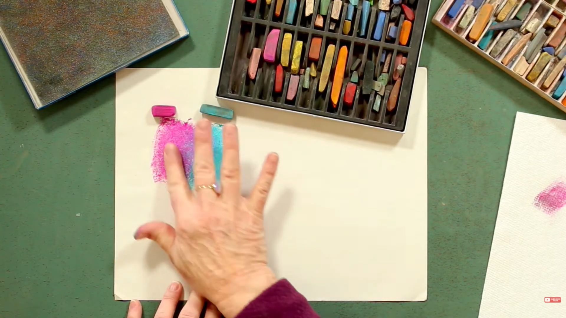 A woman's hand holds a paintbrush above a blank piece of paper, ready to create art.