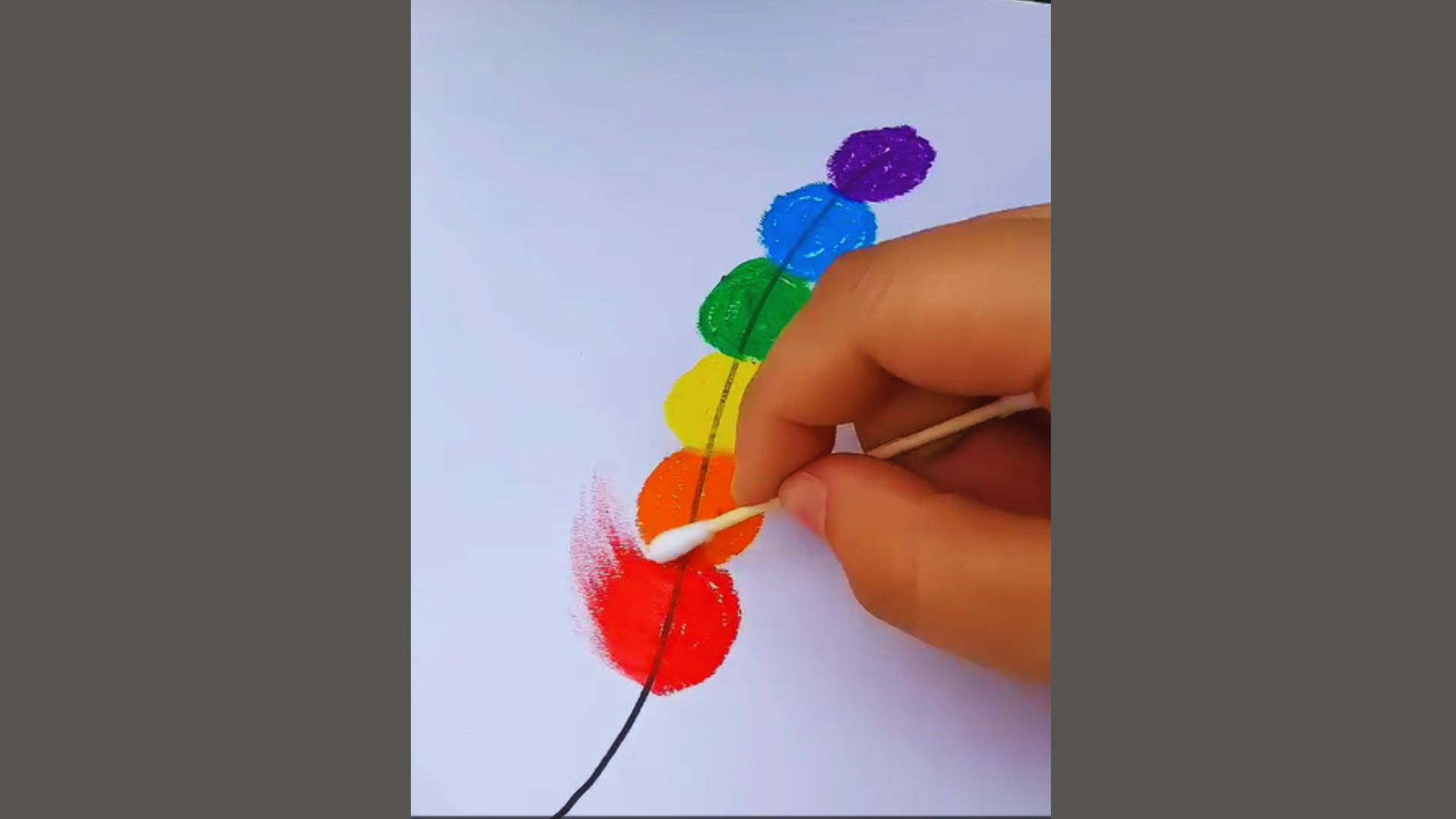 A person paints a vibrant, rainbow-colored flower on a canvas, showcasing a blend of bright hues and artistic expression.