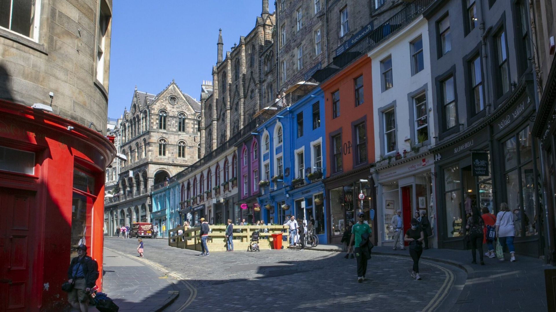 A narrow street lined with buildings, featuring people walking and engaging in various activities.