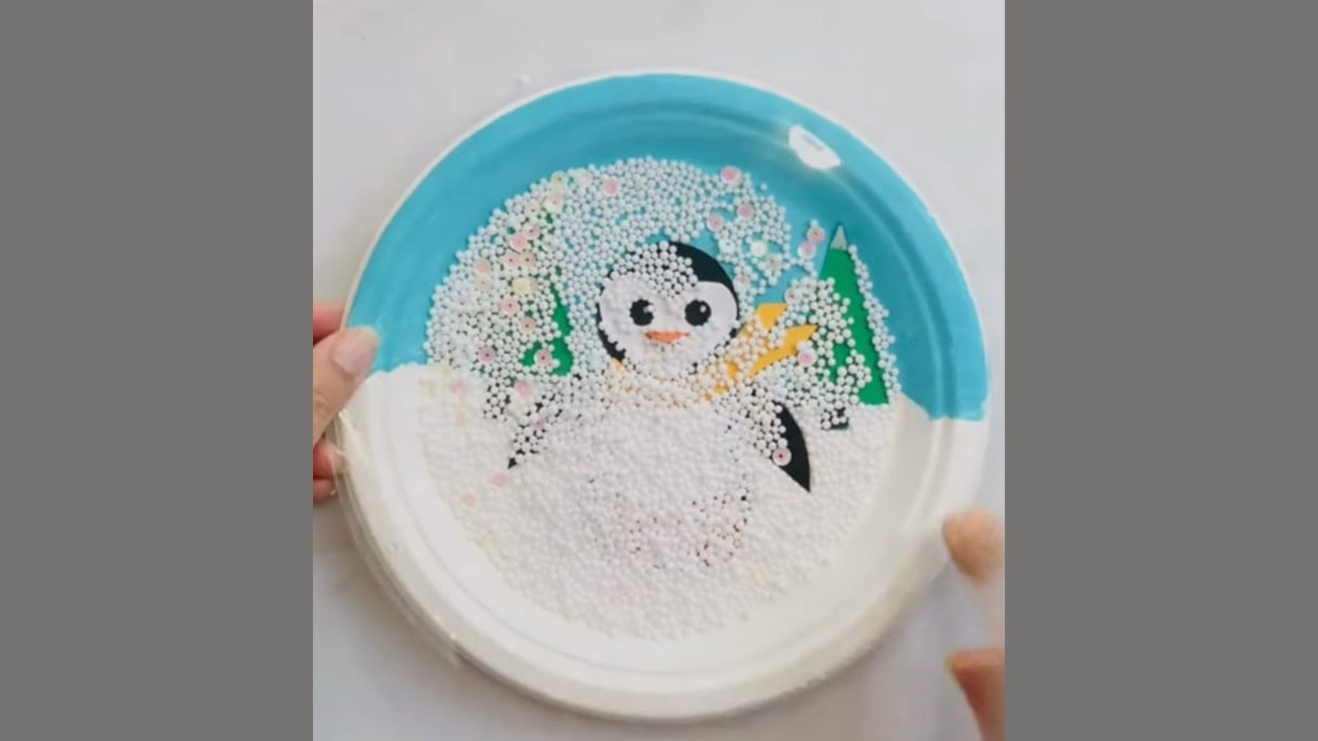 A person holds a plate featuring a small, decorative penguin on it, showcasing a whimsical presentation.