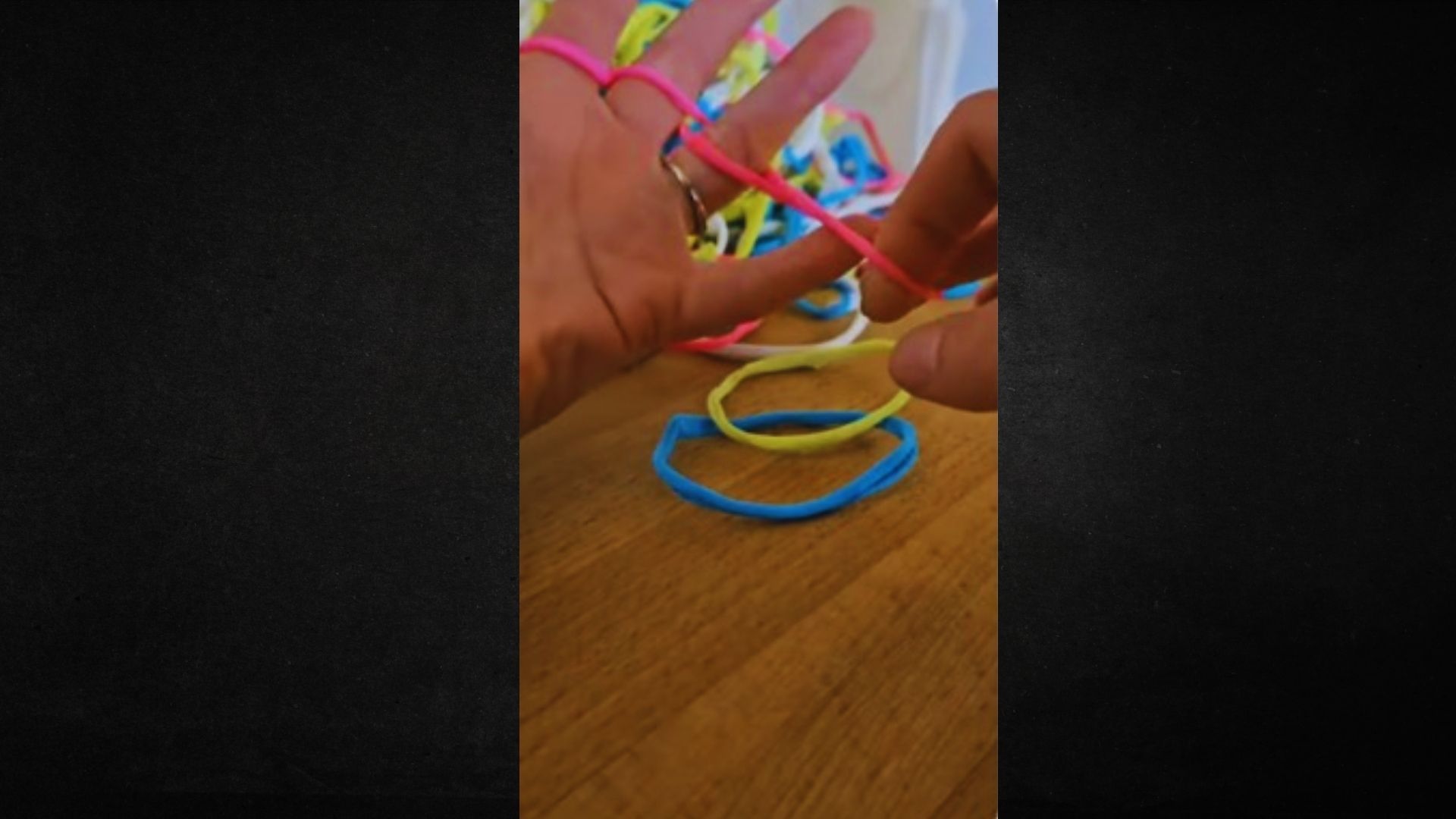 A person holds a vibrant assortment of rubber bands in their hand, showcasing various colors and sizes.