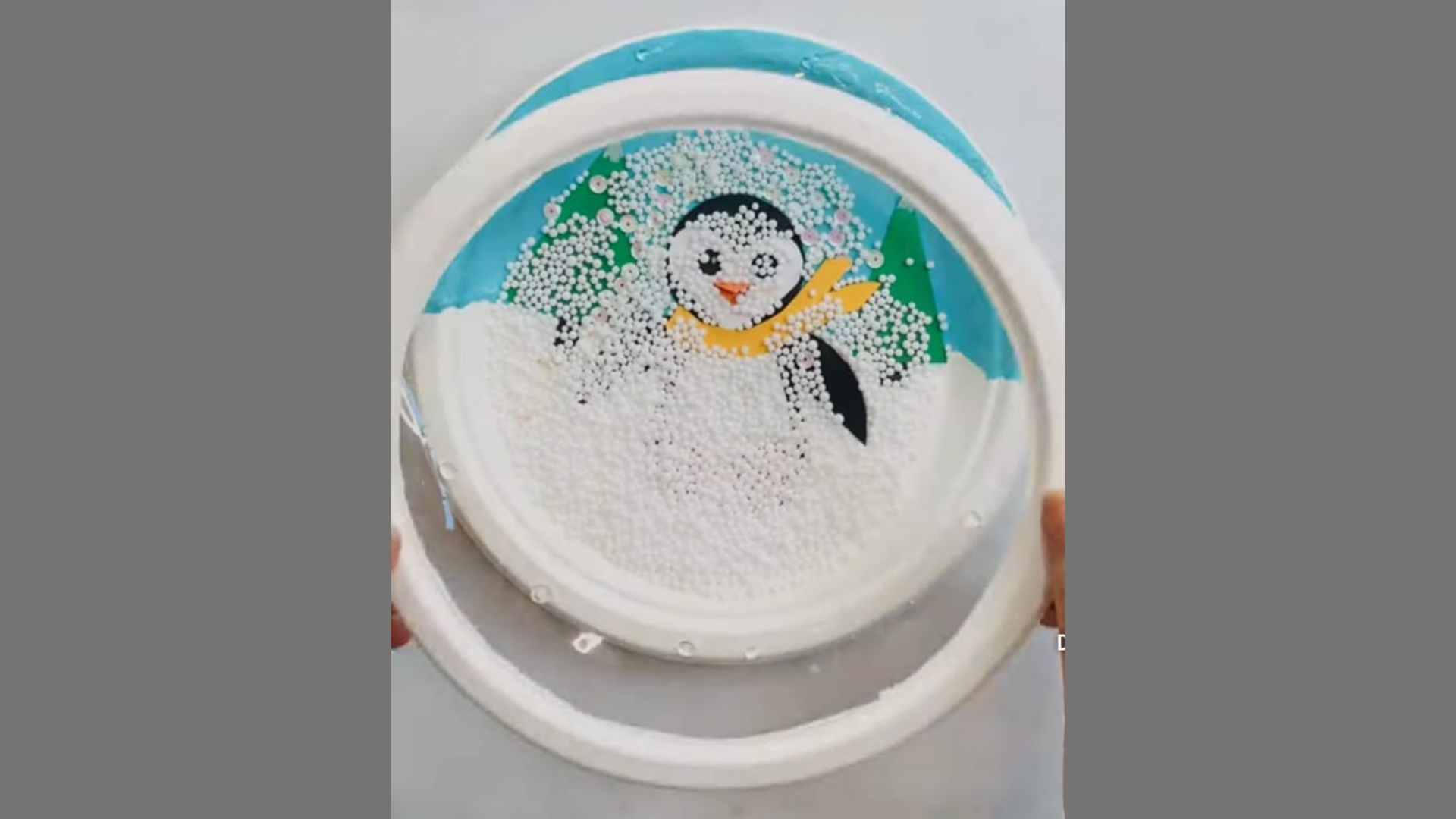 A person holds a white plate featuring a cute penguin design, showcasing a whimsical and playful presentation.