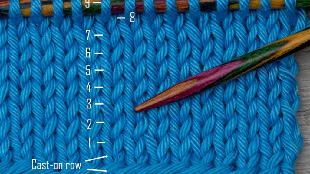 A close-up of a knitting stitch, featuring a needle and colorful yarn intertwined.