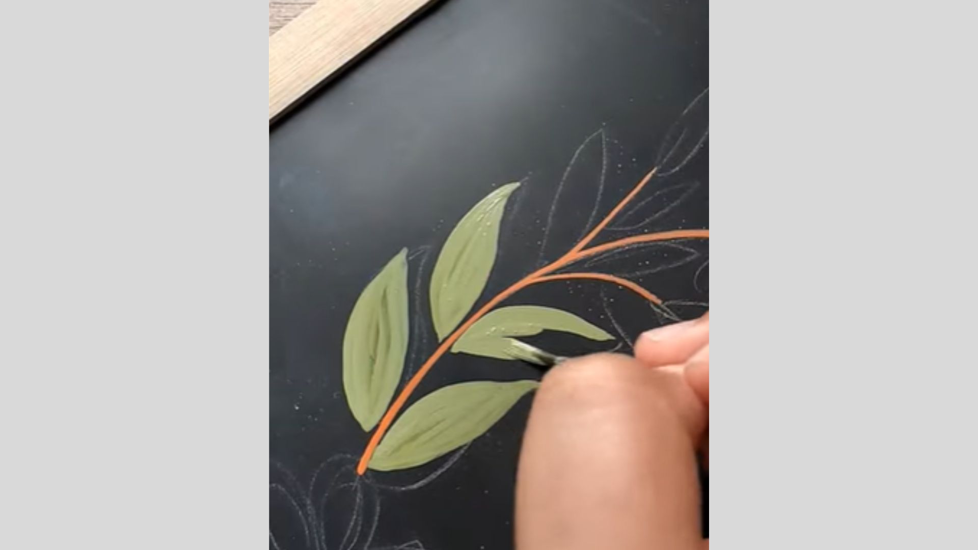 Green paint applied neatly inside leaf shapes along outlined branch design.