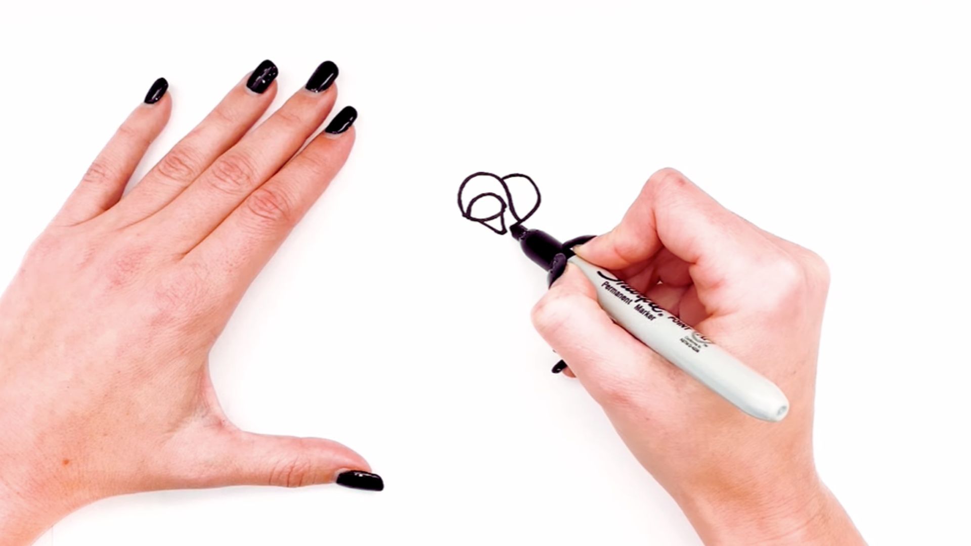 "A person using a marker to draw a heart shape on a piece of paper."