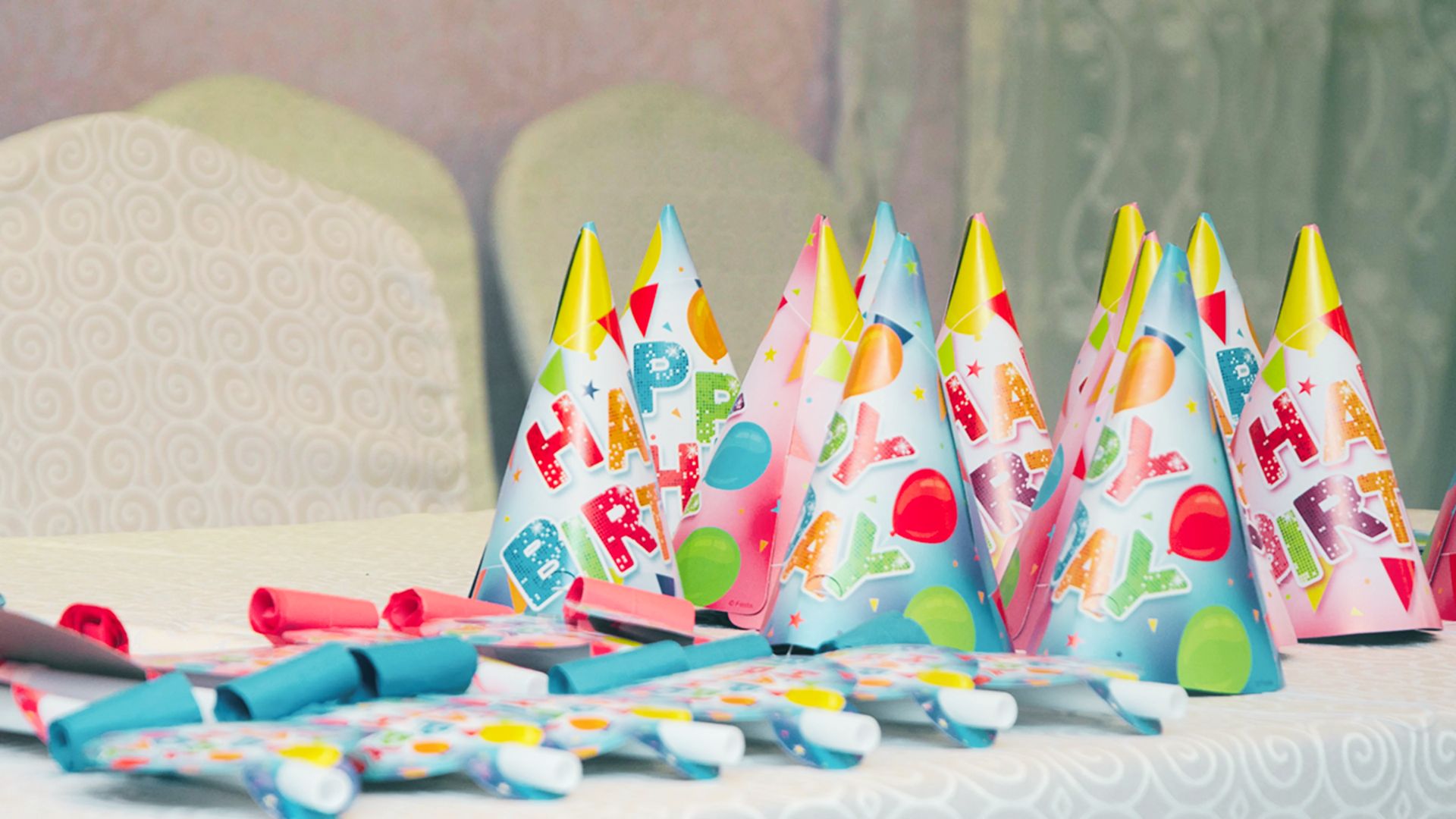 Colorful “Happy Birthday” paper party hats with balloon designs on a table