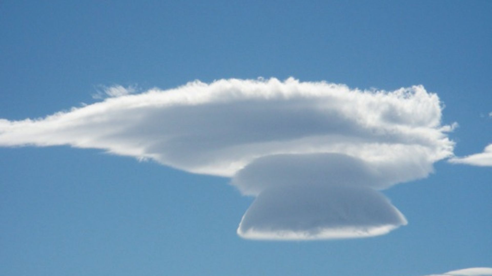 UFO-like layers floating in a clear blue sky, great reference for realistic cloud drawing.