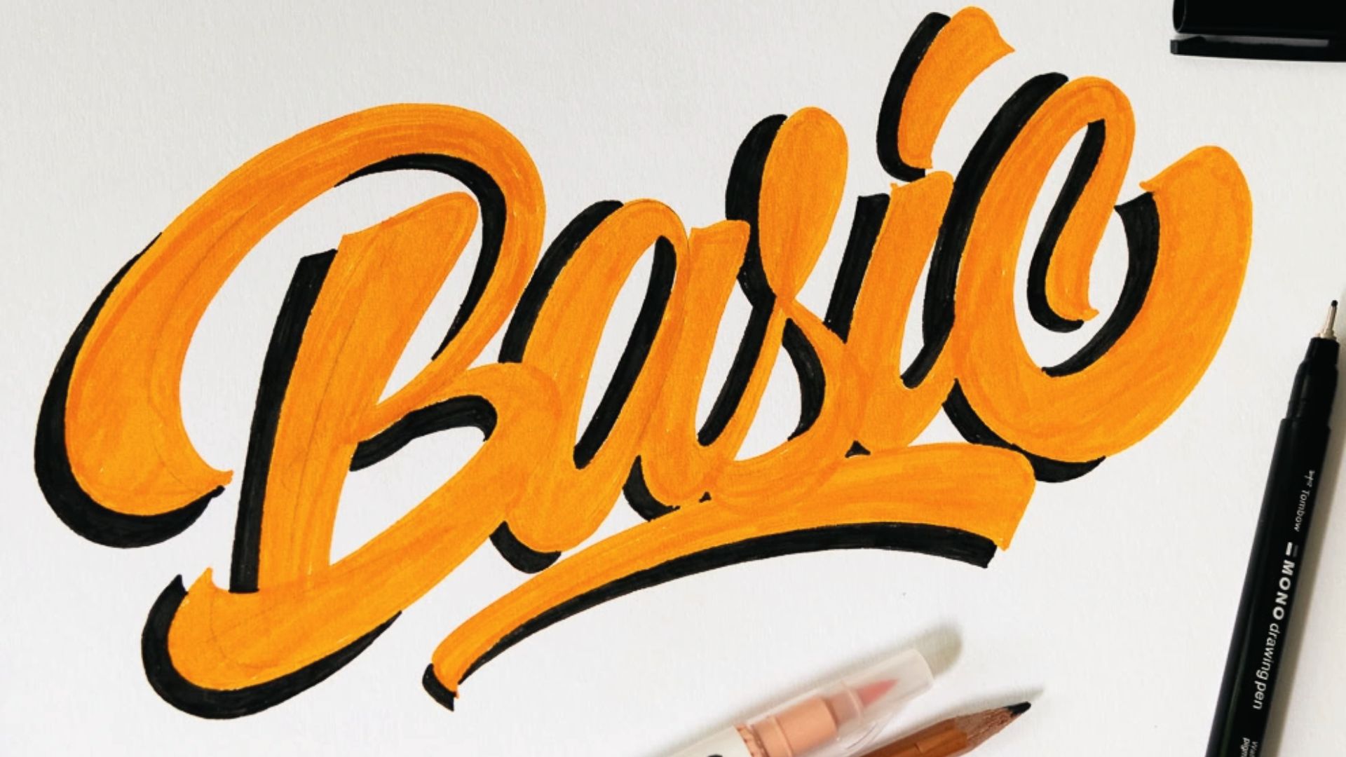 Close-up of the word “Basic” in thick orange brush lettering with black offset shadow on white paper.