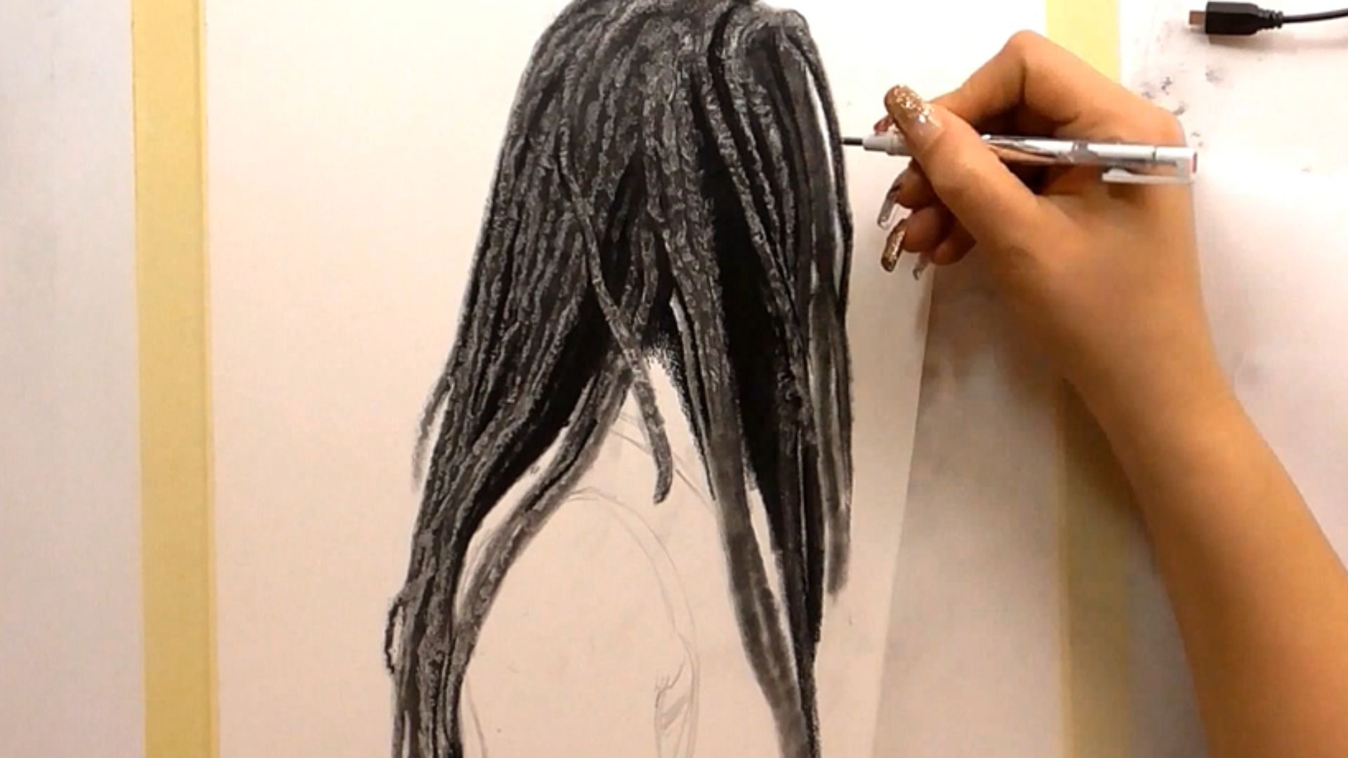 "A person sketching a black and white illustration of a woman's flowing hair on a blank canvas."