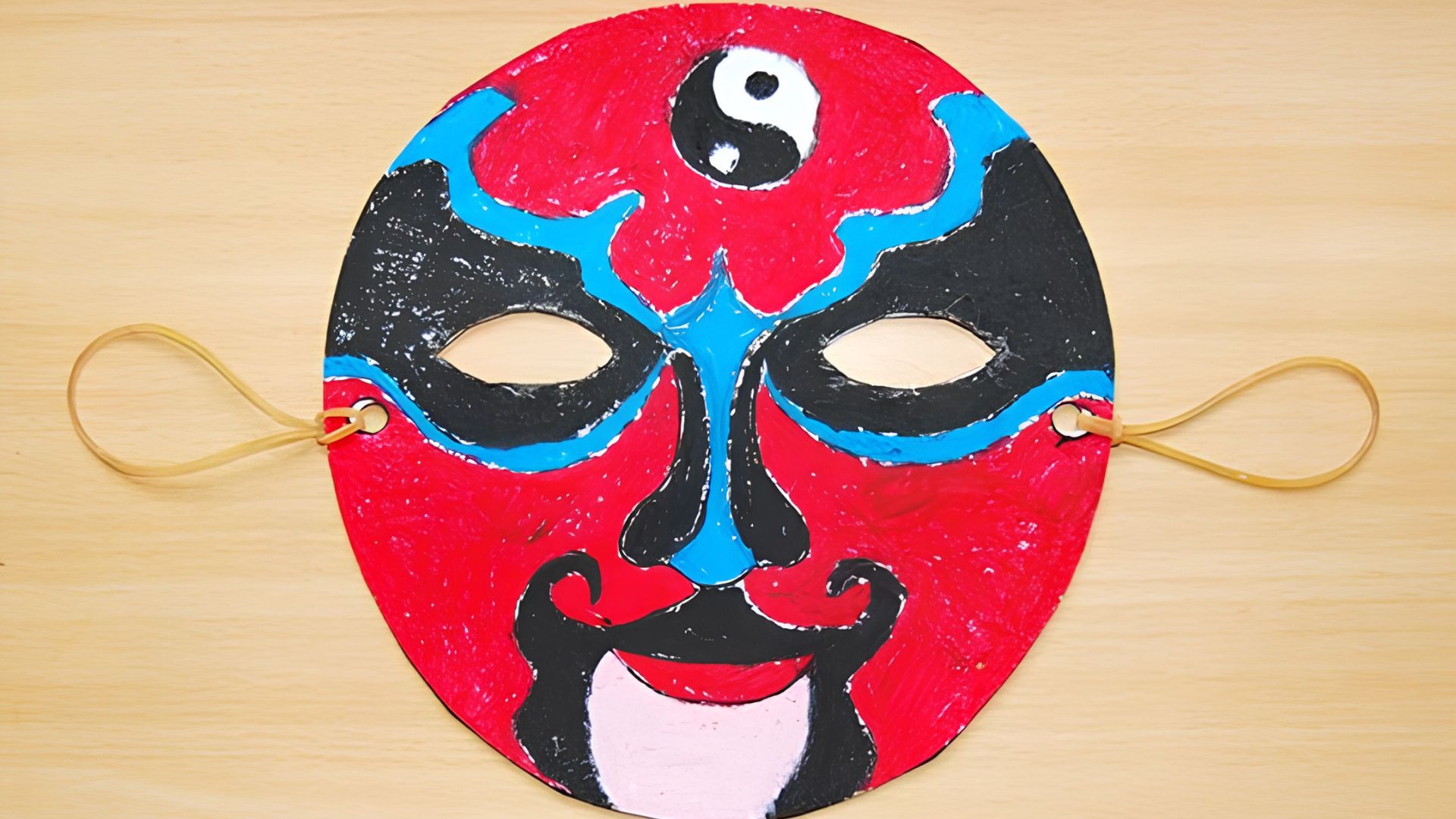 A colorful paper mask featuring a red, blue, and black design, inspired by African mask drawing ideas for beginners.