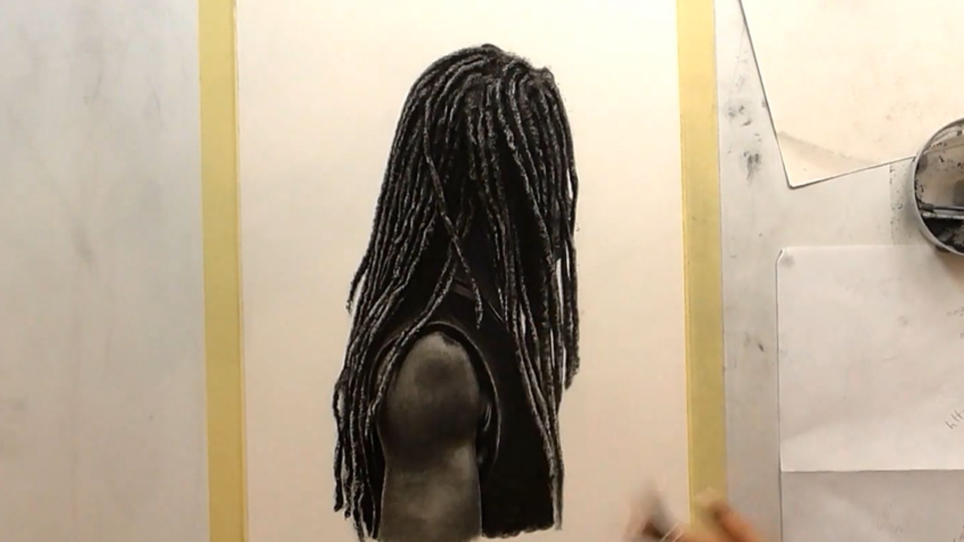 "A person sketches a black and white portrait of a woman with dreadlocks on a blank canvas."